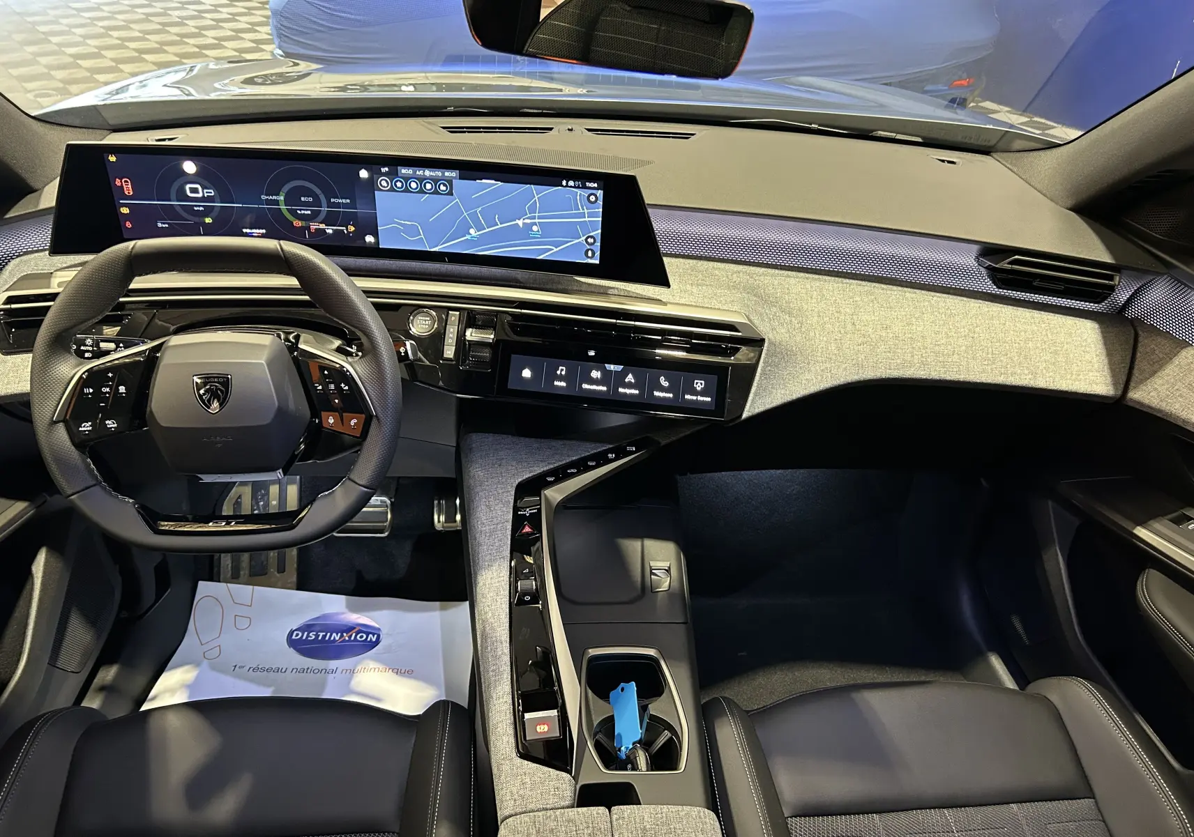 Vue intérieure avant du Peugeot 5008 bleu Ingaro, tableau de bord numérique et volant multifonction moderne.