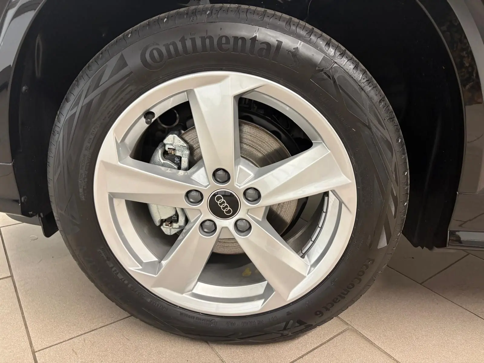Gros plan sur la roue avant droite d’un Audi Q2 35 TFSI 150 S tronic 7 S line noir mythic avec jante alliage argentée.