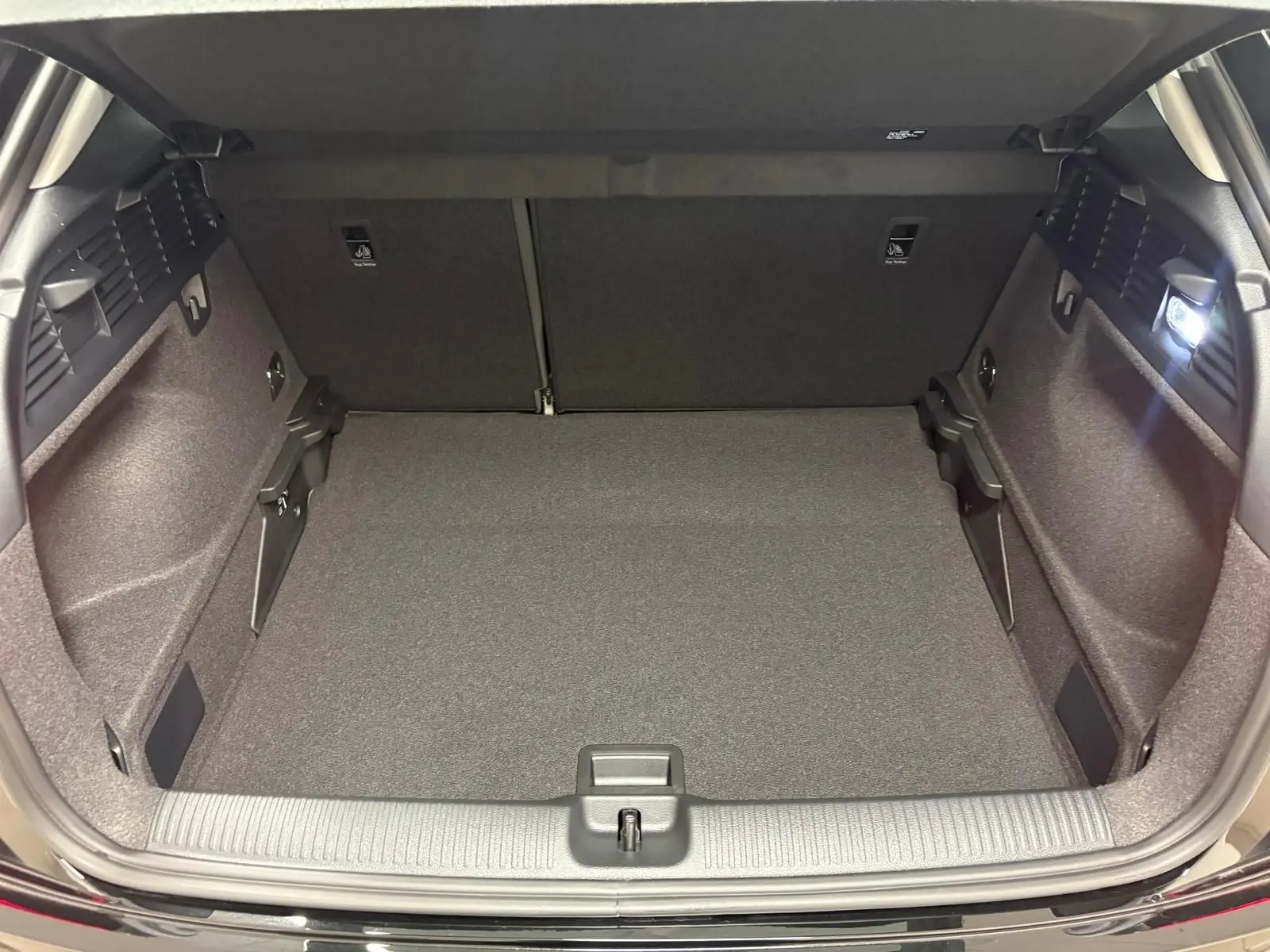 Coffre ouvert d’un Audi Q2 35 TFSI S Line noir Mythic, vue de l’arrière montrant l’espace de chargement vide et éclairé.