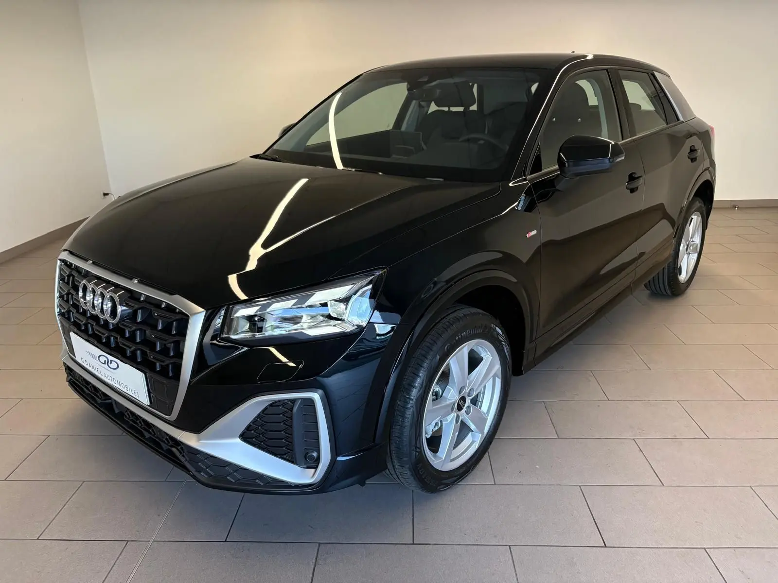 Audi Q2 35 TFSI S line noir mythic vue 3/4 avant droit dans un showroom intérieur lumineux.