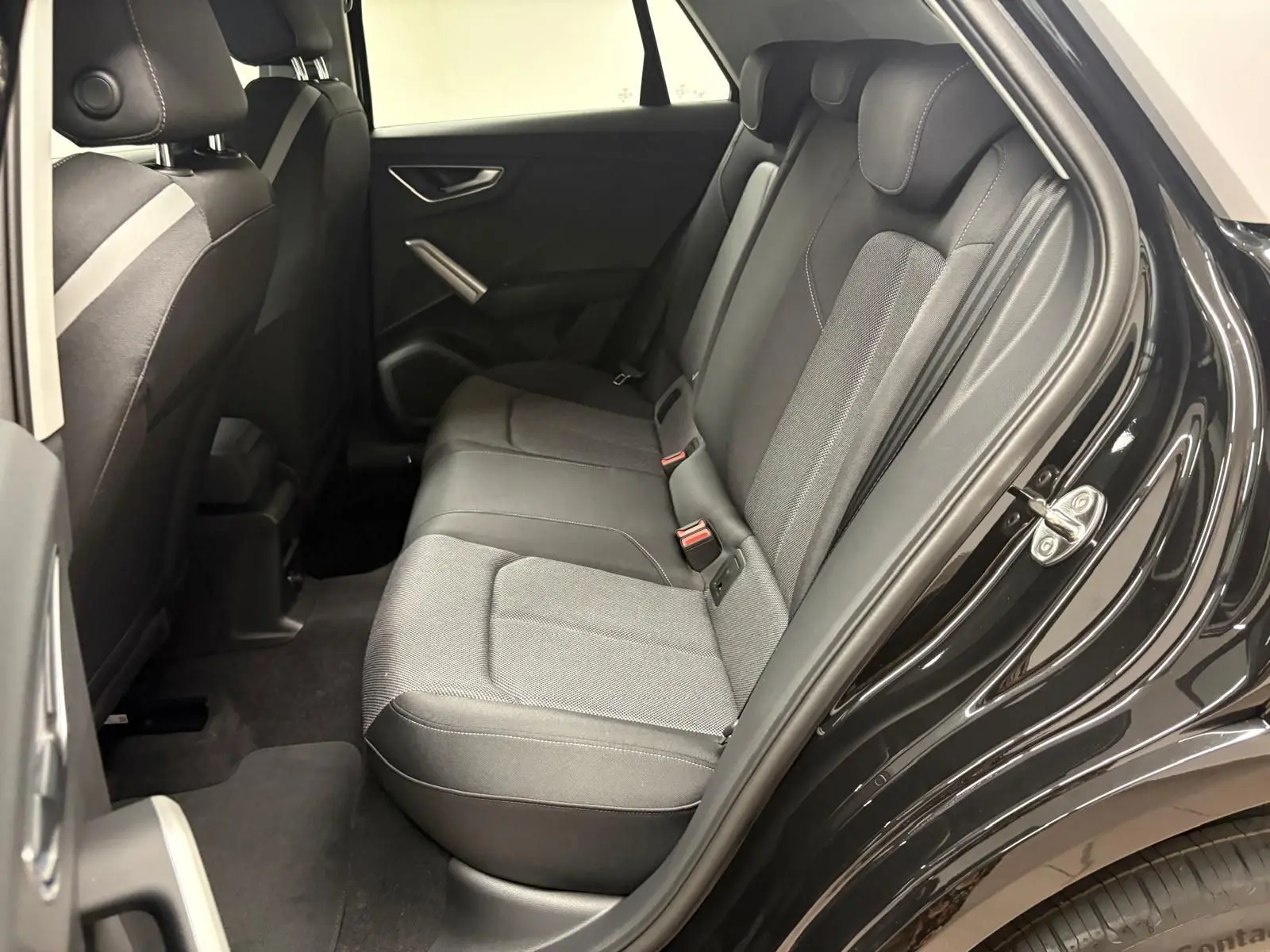Vue intérieure côté gauche des sièges arrière en tissu gris du SUV Audi Q2 35 TFSI S Line noir mythic, porte arrière ouverte.