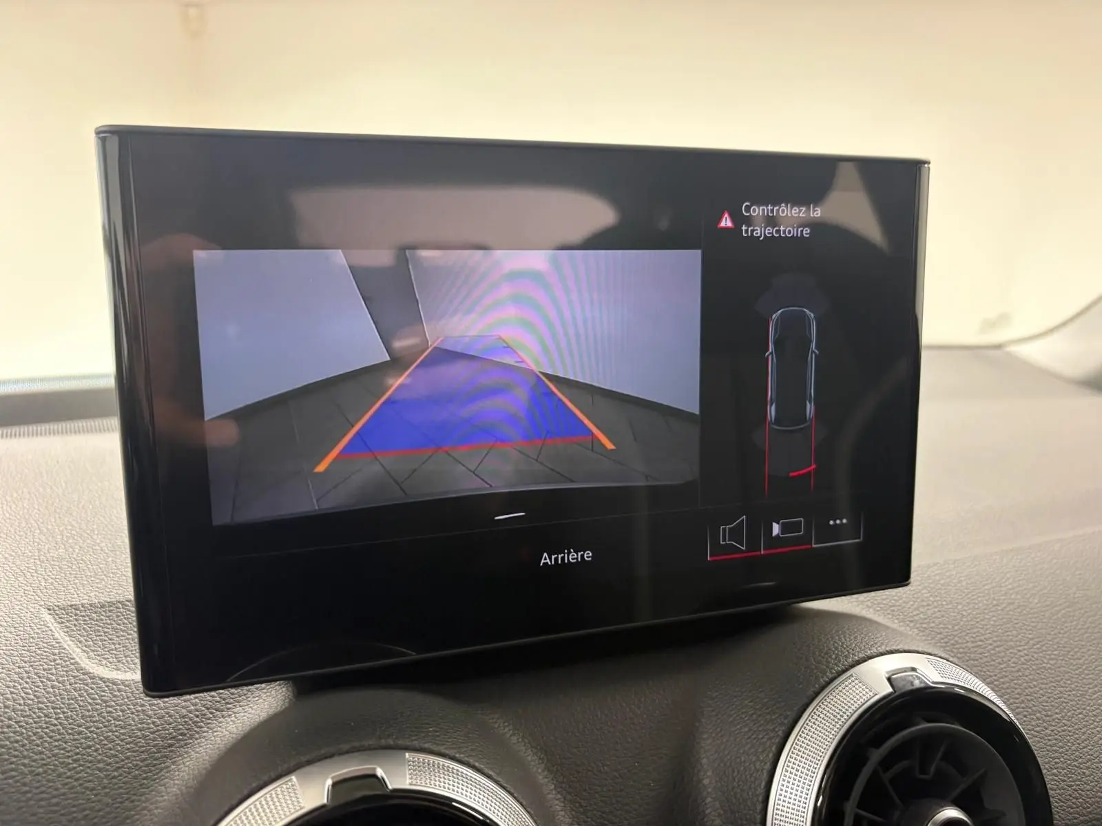 Écran central affichant la caméra de recul et l'alerte de trajectoire dans l'Audi Q2 Noir Mythic, vue intérieure.