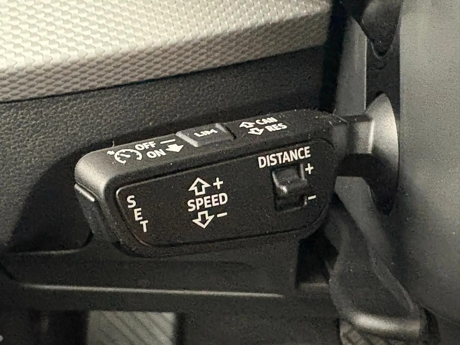 Gros plan sur la commande de régulateur de vitesse adaptatif dans l’habitacle d’un Audi Q2 noir Mythic.
