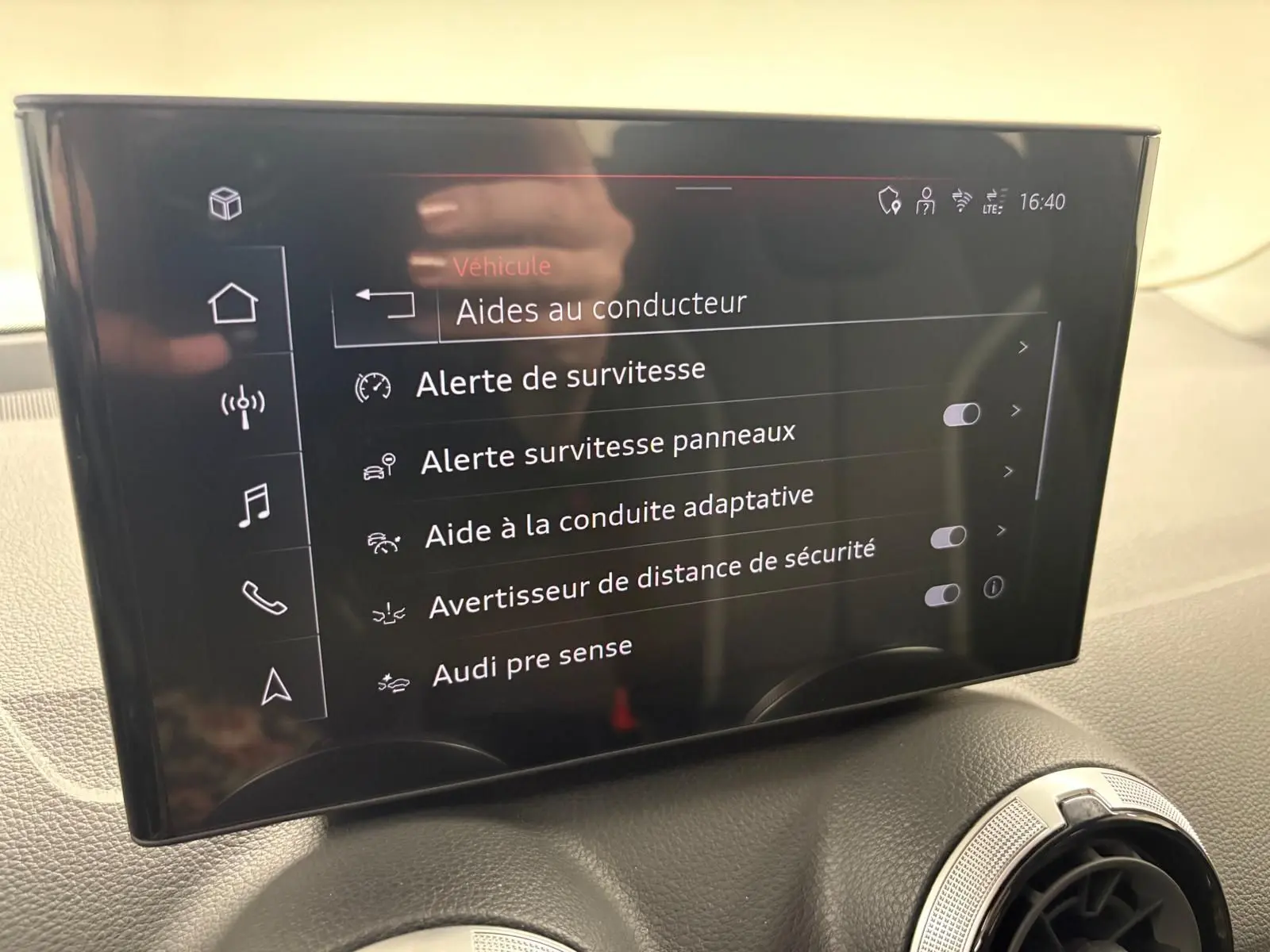 Écran tactile central de l'Audi Q2 35 TFSI S Line 2026 affichant les aides à la conduite, intérieur noir.