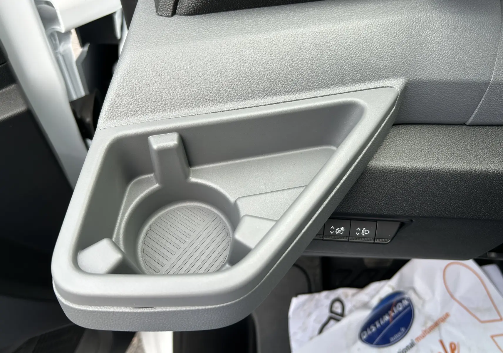 Gros plan sur le porte-gobelet gris intégré côté conducteur du tableau de bord du Renault Master blanc 2025.