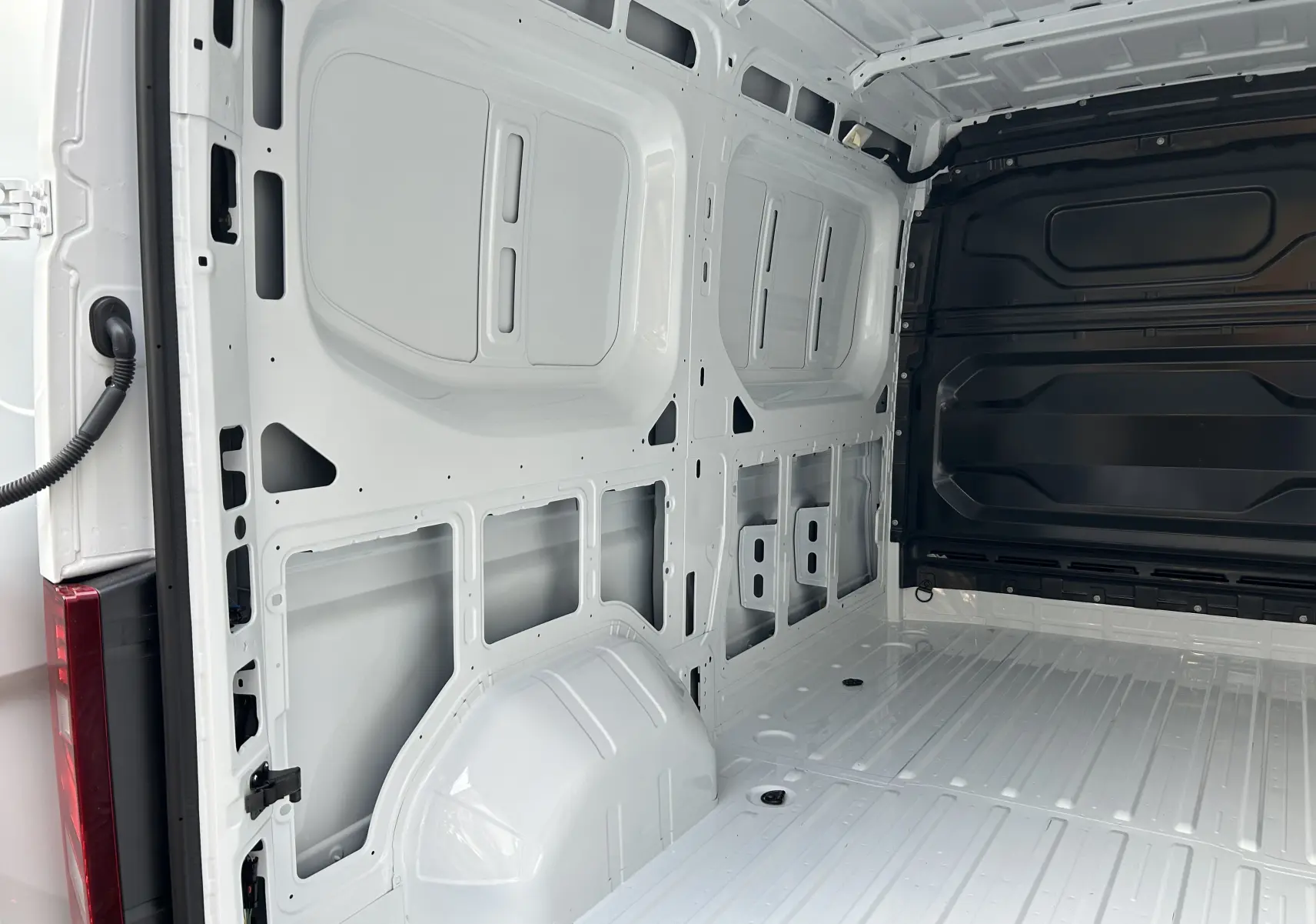 Intérieur du fourgon Renault Master blanc vu en angle, montrant la paroi et le plancher métalliques vides.