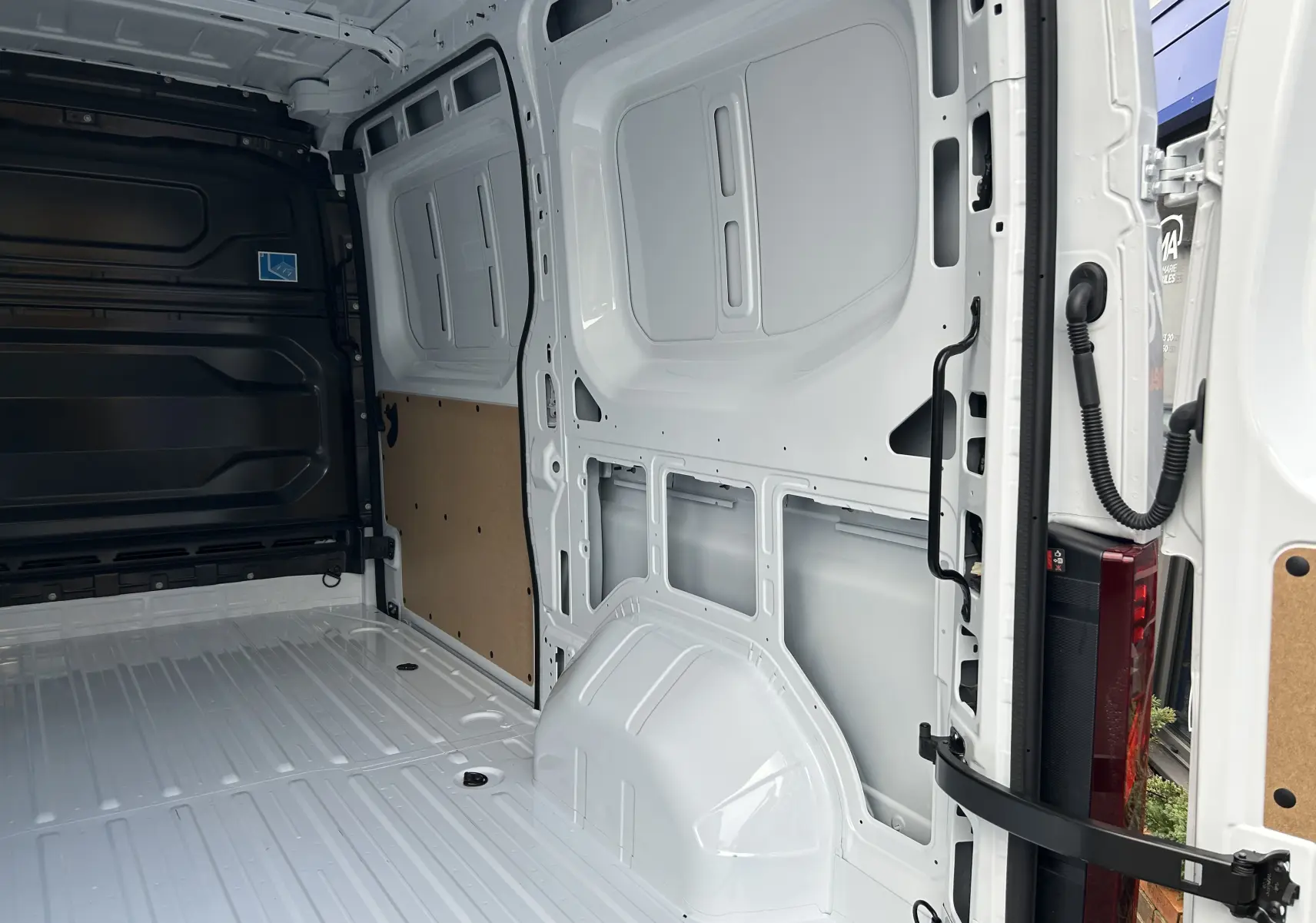Vue intérieure arrière du fourgon blanc Renault Master IV L2H2, montrant l'espace de chargement vide et les parois métalliques.