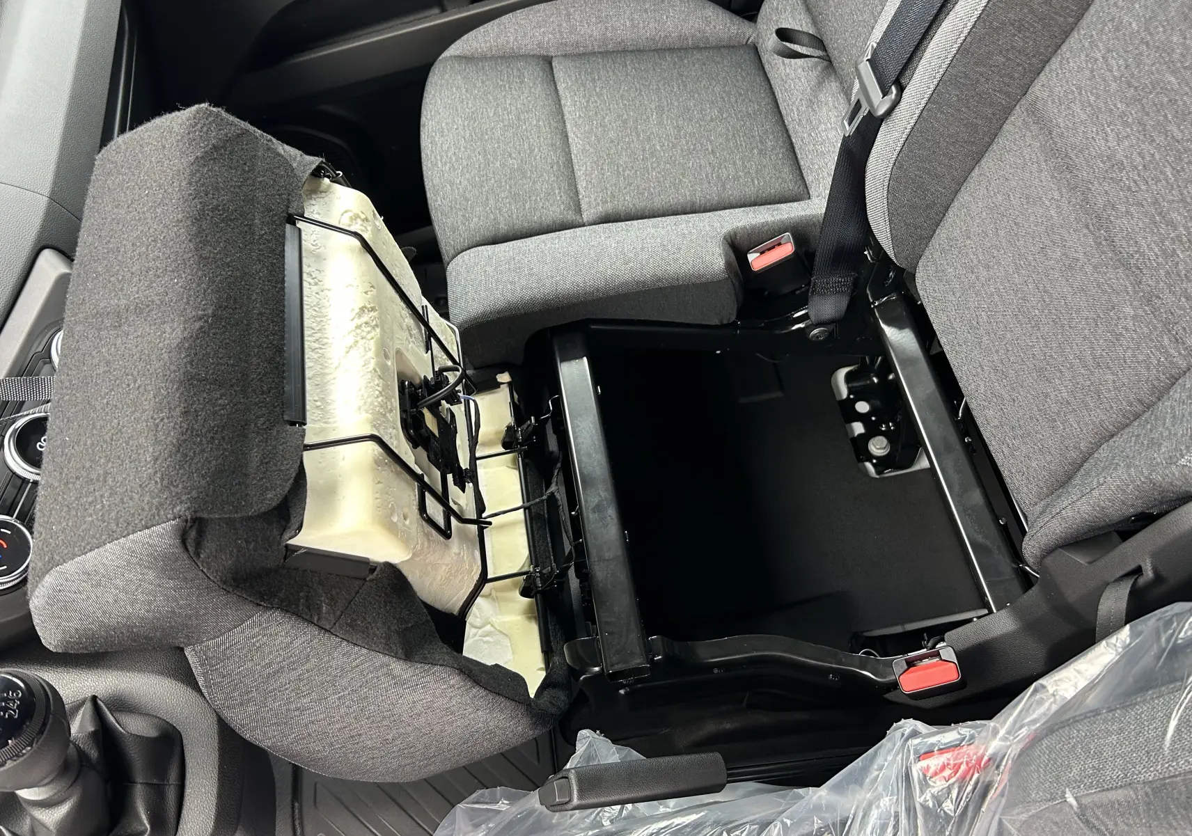 Vue intérieure du siège conducteur relevé du Renault Master IV L2H2 blanc, montrant le rangement sous le siège et la sellerie grise.