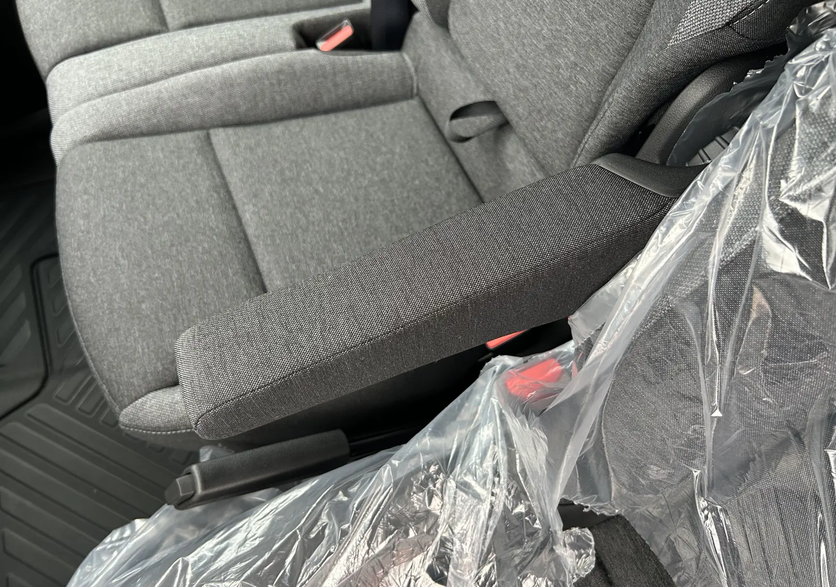 Gros plan sur l'accoudoir et siège tissu gris du Renault Master 2025, intérieur protégé par une housse plastique.