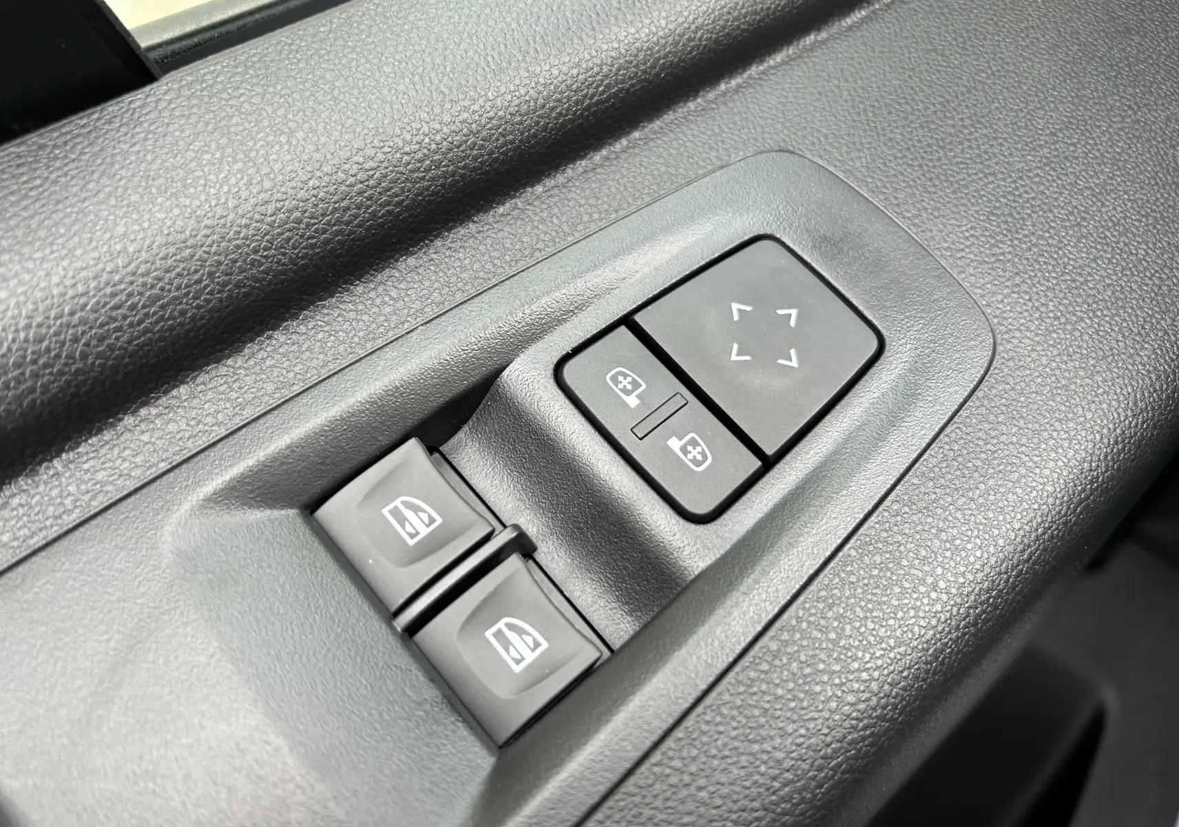 Gros plan sur les commandes de réglage des rétroviseurs et des vitres électriques côté conducteur du Renault Master blanc 2025.