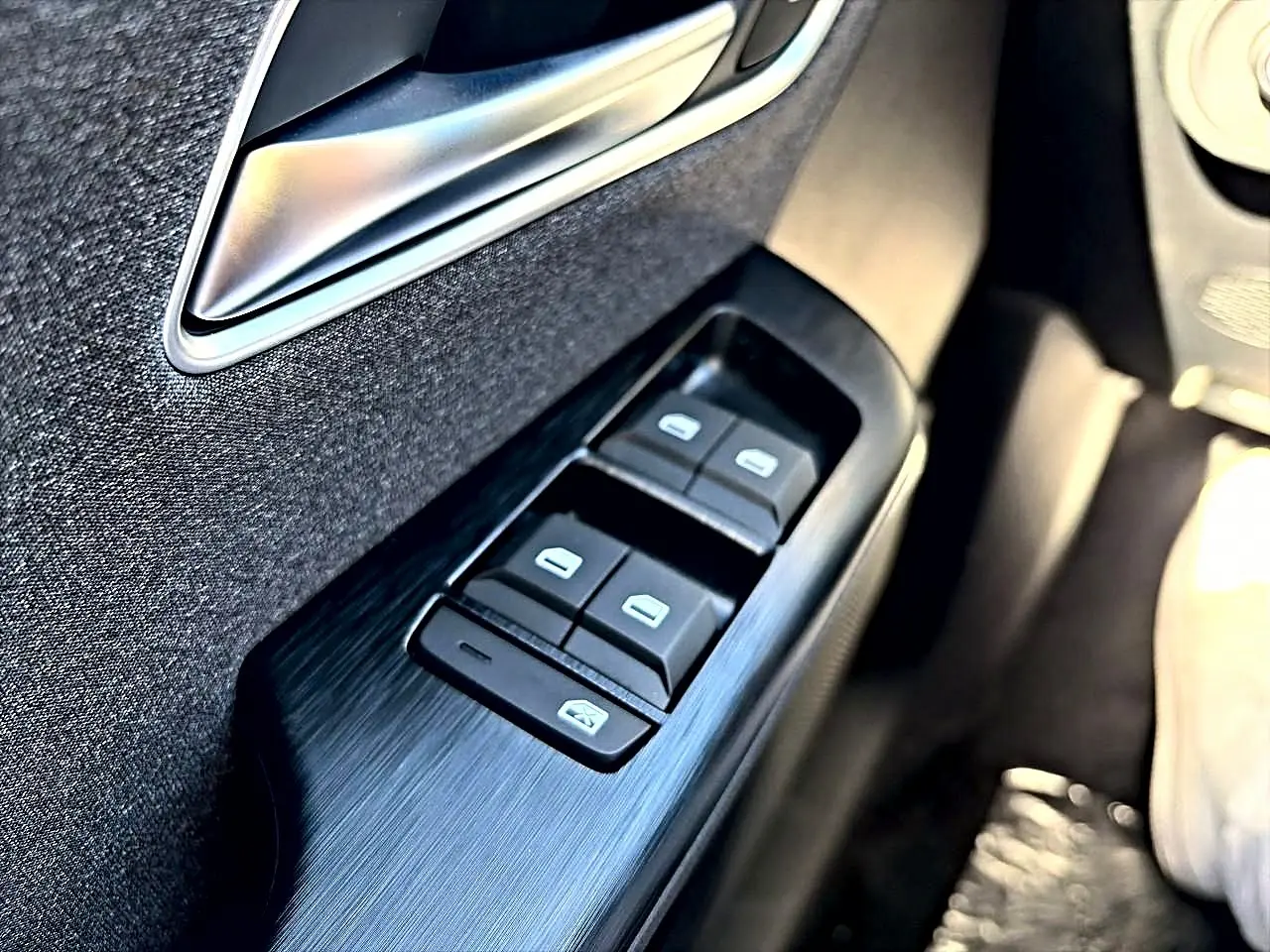 Gros plan sur les commandes des vitres électriques côté conducteur d’un MG Motor ZS noir hybride 2026.