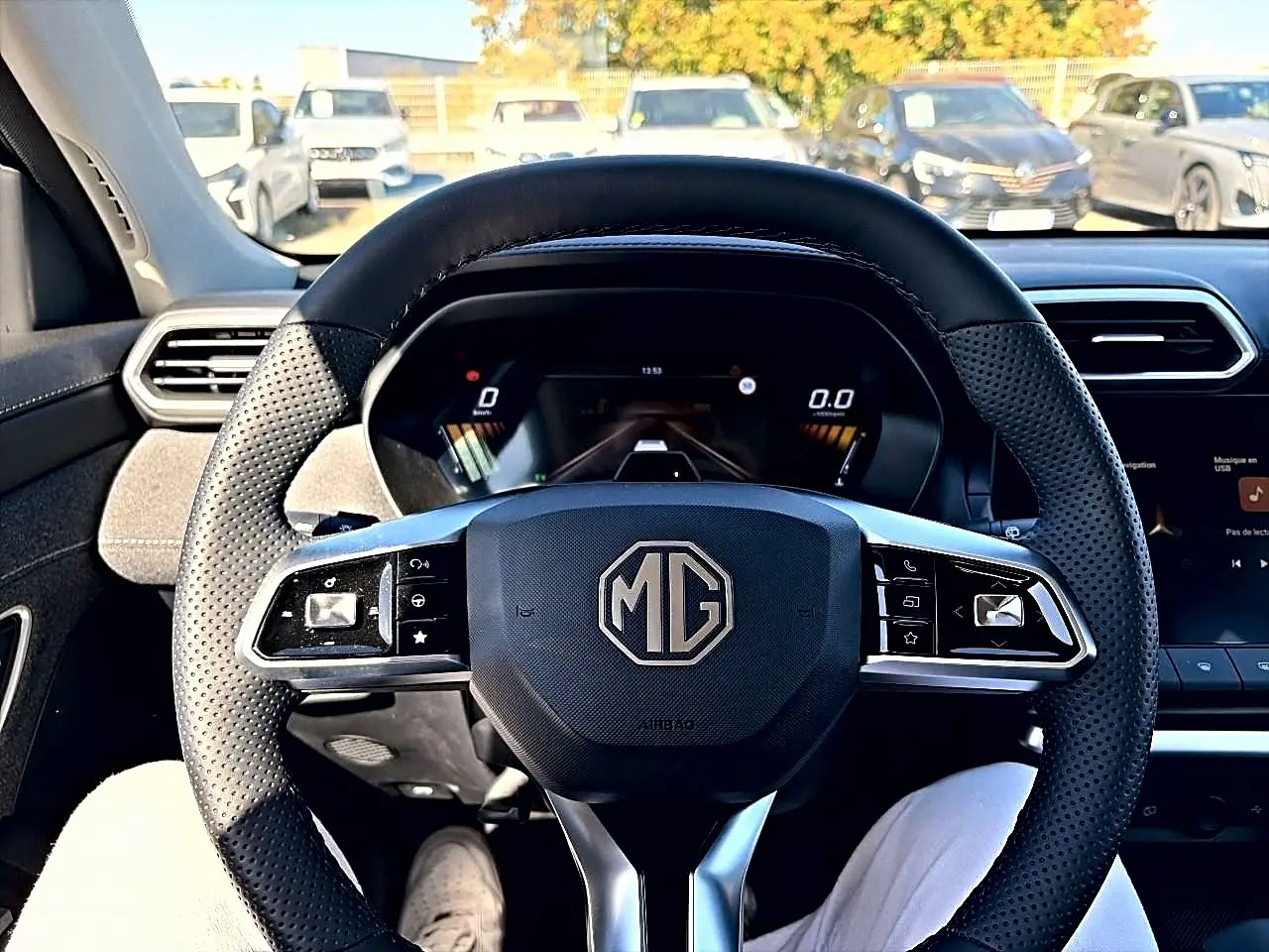 Vue centrée sur le volant noir perforé du MG ZS 1.5 hybrid 197 avec tableau de bord numérique et écran tactile visible.