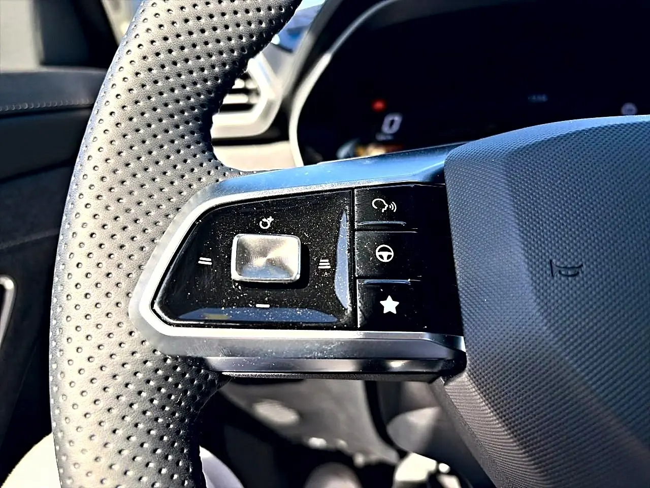 Gros plan sur les commandes à gauche du volant perforé noir du MG Motor ZS 1.5 hybrid 197 standard 2026.