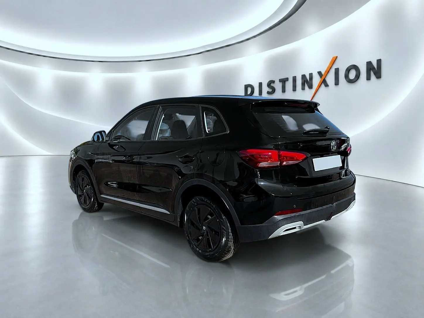 MG Motor ZS hybride noir en vue 3/4 arrière droit dans un showroom lumineux avec logo Distinxion en arrière-plan.