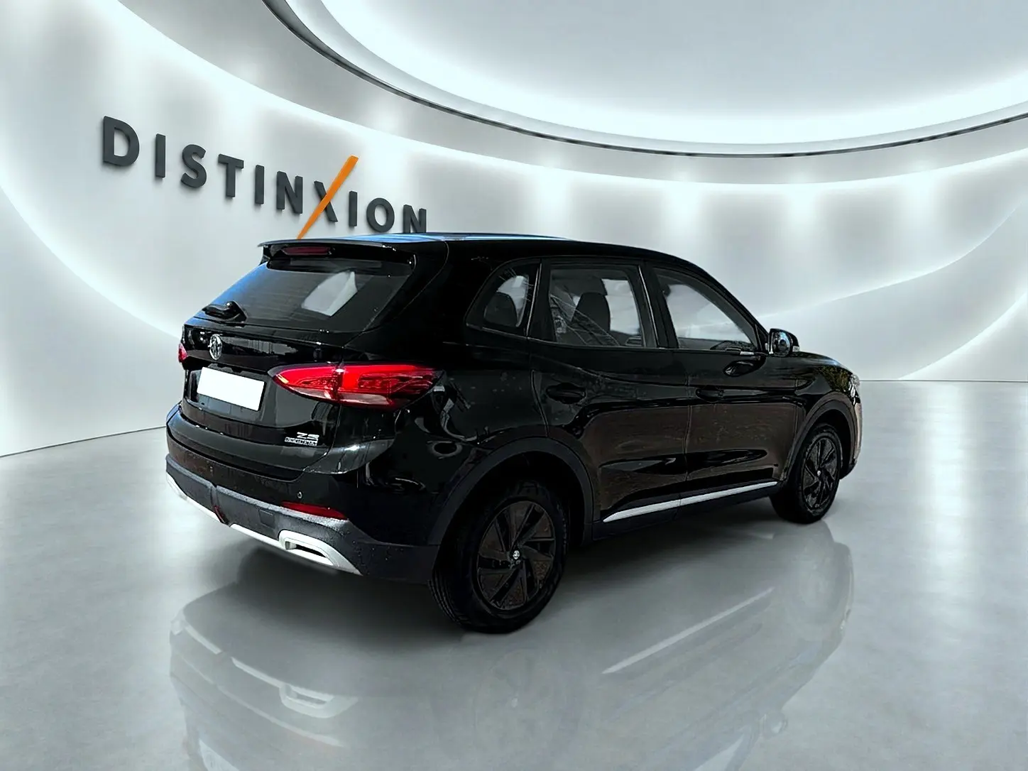 Vue 3/4 arrière droite du SUV MG ZS noir 2026 avec feux arrière LED et becquet arrière dans un showroom lumineux.