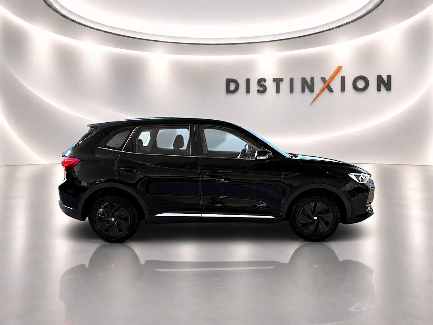 MG ZS 1.5 hybrid noir en profil droit dans un showroom lumineux avec jantes noires et becquet arrière.