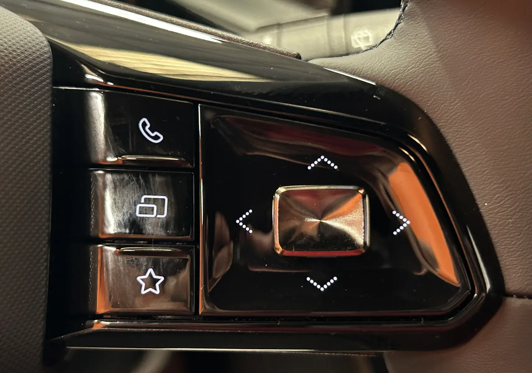 Gros plan sur les commandes au volant du MG3 1.5 Hybrid+ 195 Luxury Pebble Black, boutons lumineux sur fond noir brillant.