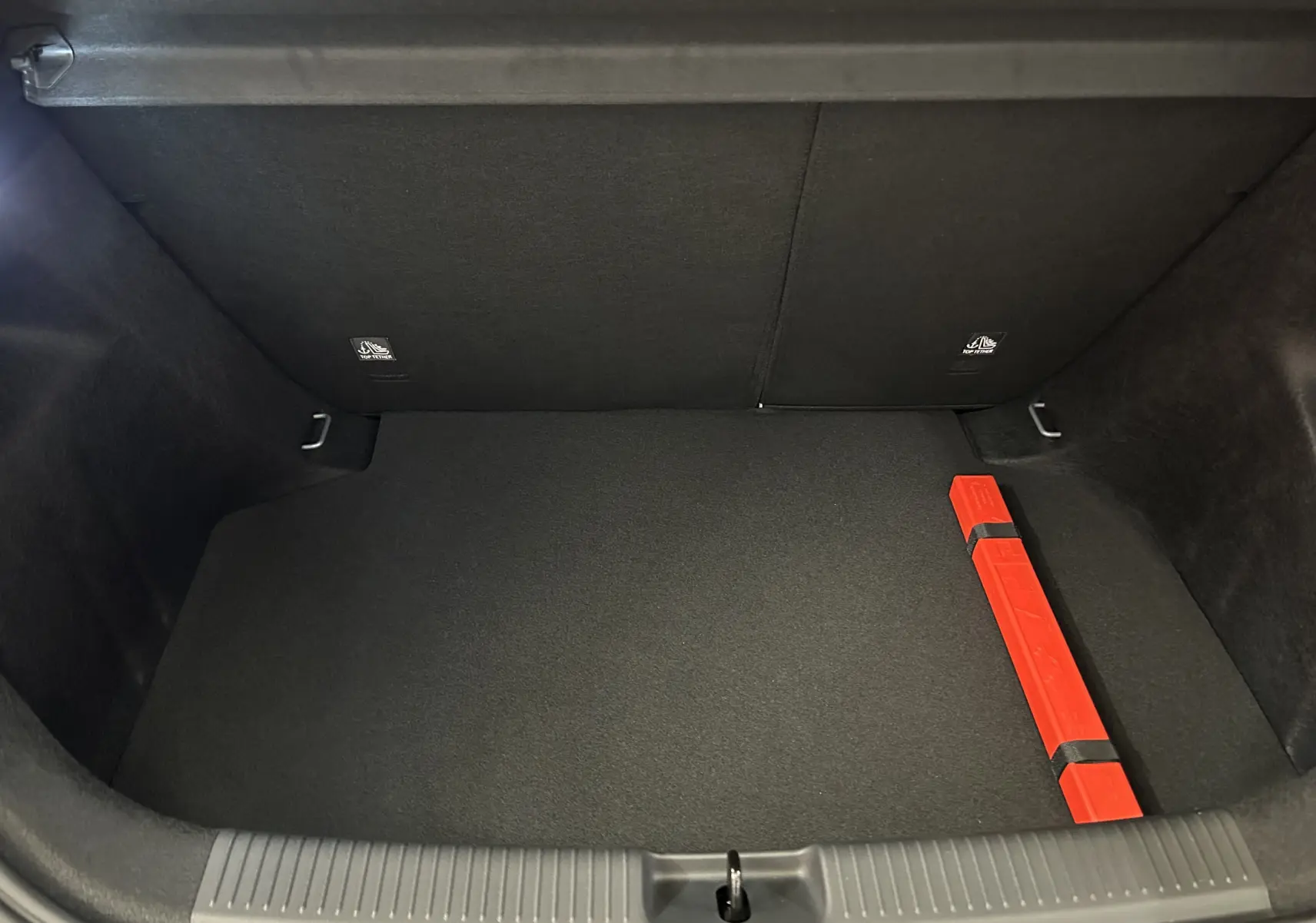Coffre ouvert de MG3 1.5 Hybrid+ Pebble Black, vue de dessus montrant un triangle de signalisation rouge à droite.