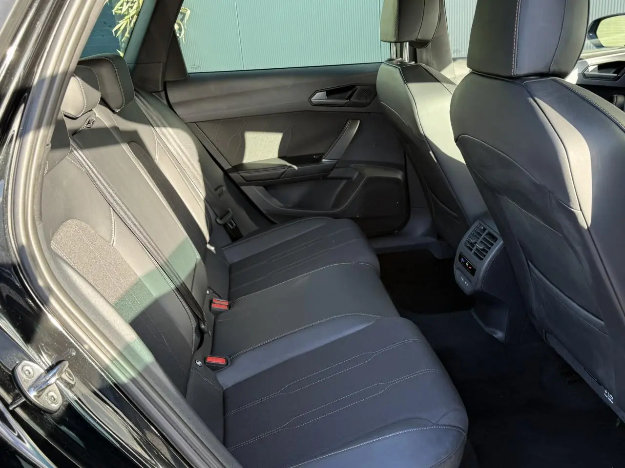 Vue intérieure côté gauche des sièges arrière noirs en cuir du CUPRA LEON ST 2025 avec coutures contrastées et aérateurs centraux.