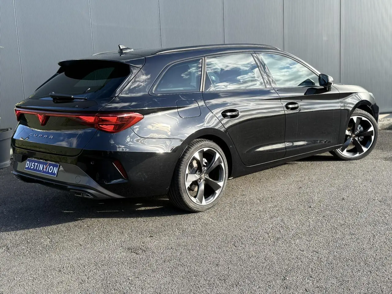 Vue 3/4 arrière droite d'une CUPRA LEON ST noire Midnight avec jantes alliage 18 pouces et bandeau lumineux arrière Tri-LED.