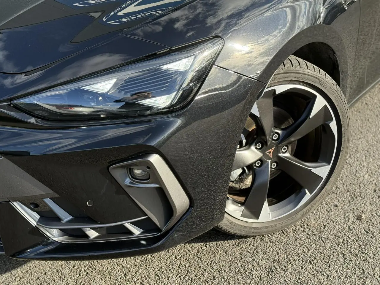 Gros plan sur l'avant droit noir Midnight de la CUPRA LEON ST 2025, mettant en valeur le projecteur Tri-LED et la jante alliage 18 pouces.