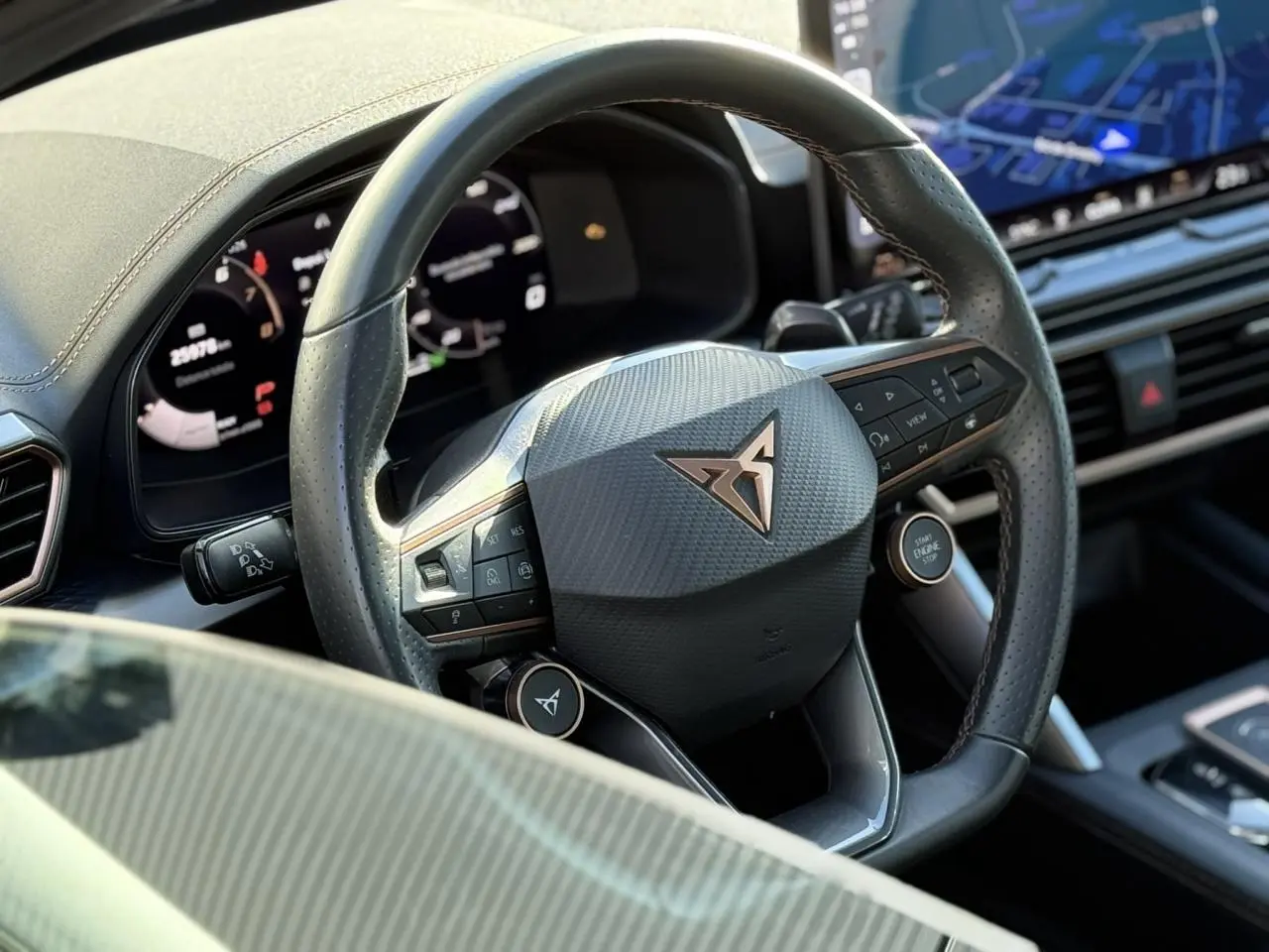 Gros plan sur le volant en cuir perforé avec logo CUPRA et tableau de bord numérique du Leon ST noir Midnight.