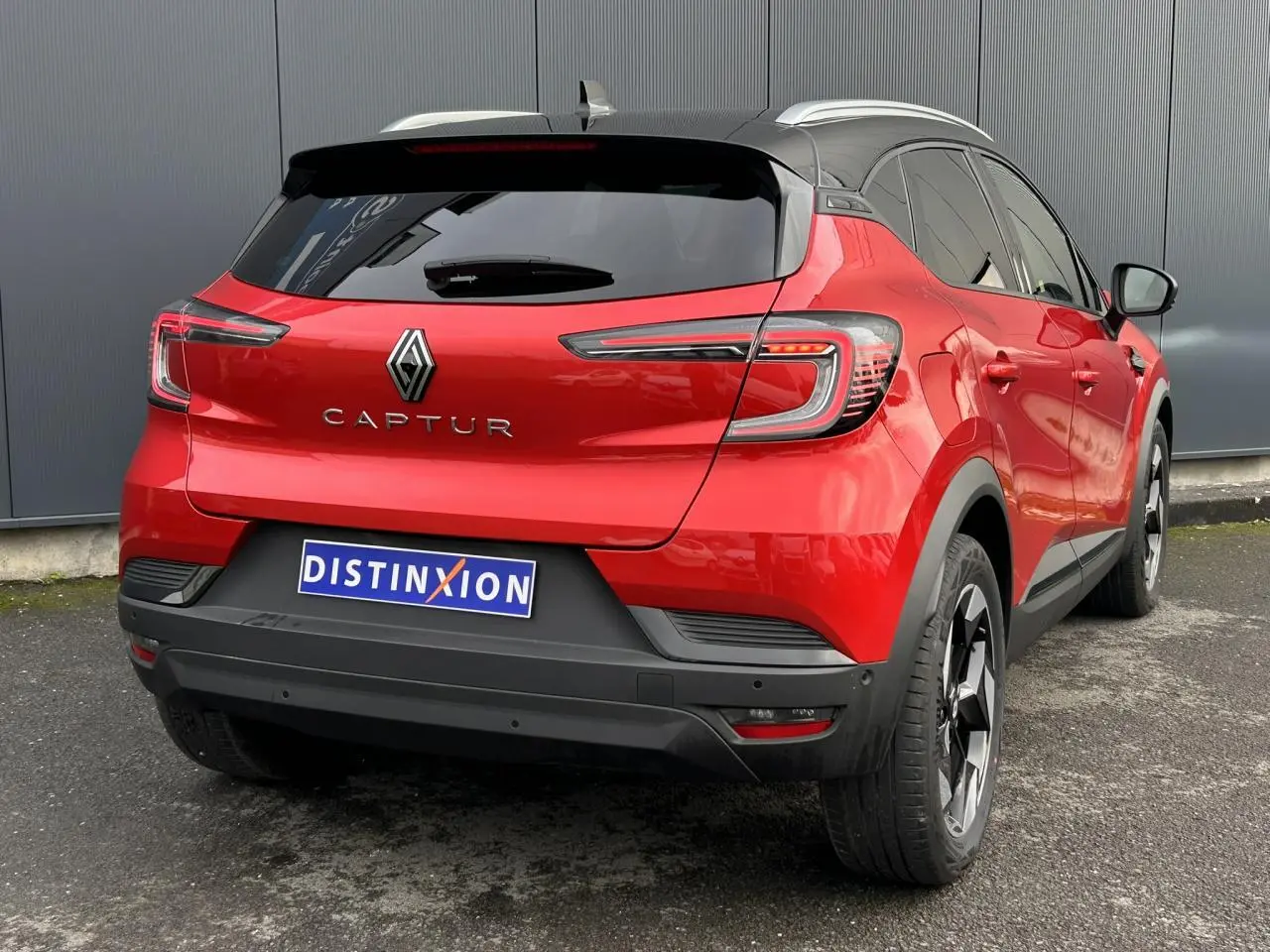 Vue 3/4 arrière droite du Renault Captur 2025 rouge Flamme avec toit noir et jantes alu 18 pouces diamantées noires.