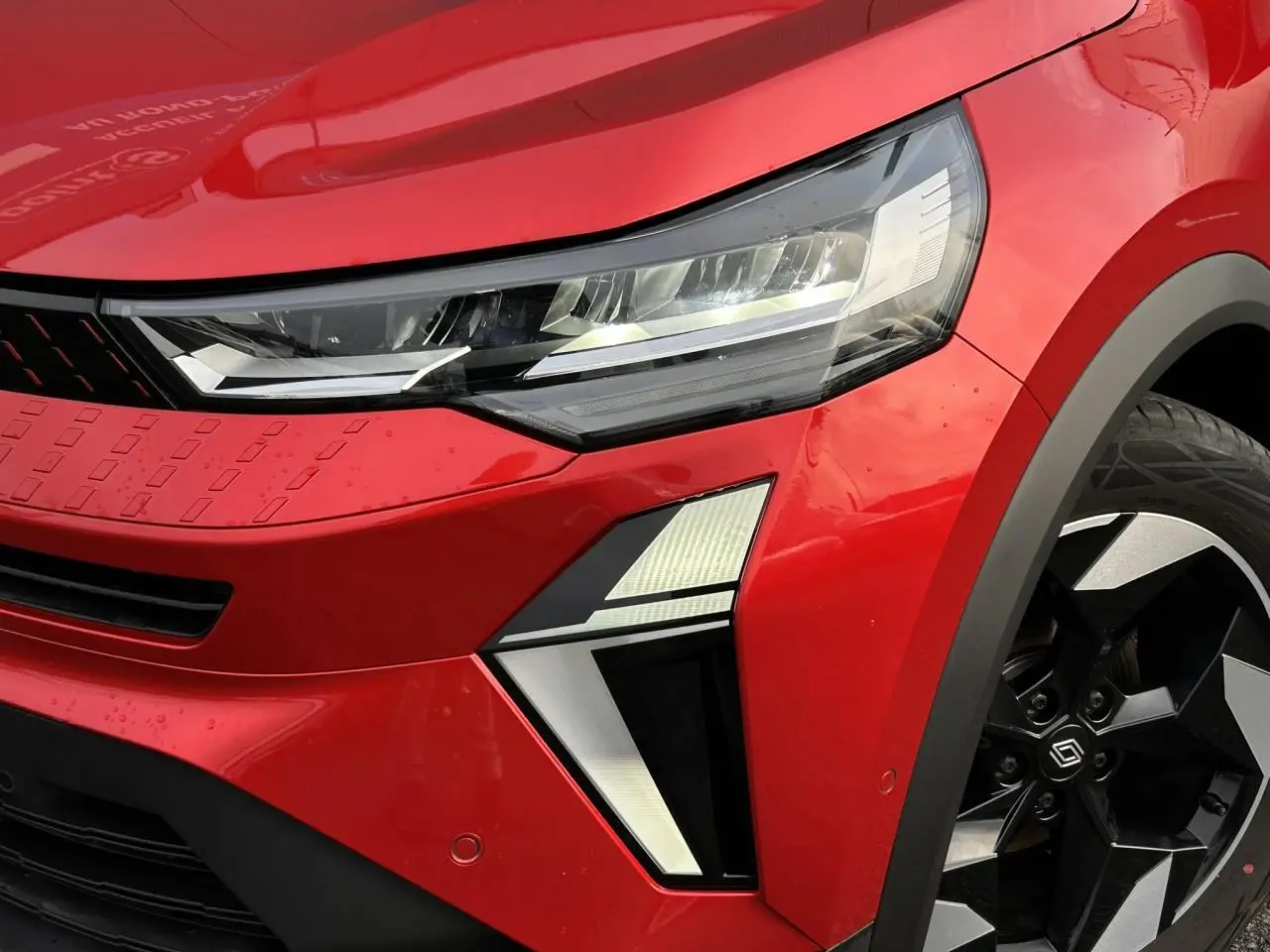 Gros plan sur l'avant droit du Renault Captur 2025 Rouge Flamme avec phares LED et jantes alu diamantées noires.