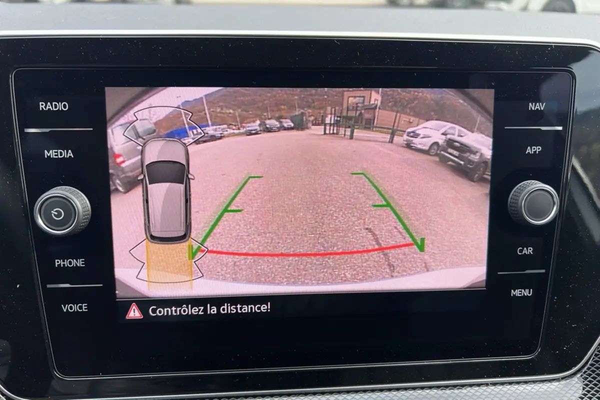 Affichage de la caméra de recul du Volkswagen T-Cross gris argent, avec guidage de trajectoire et vue arrière du parking.