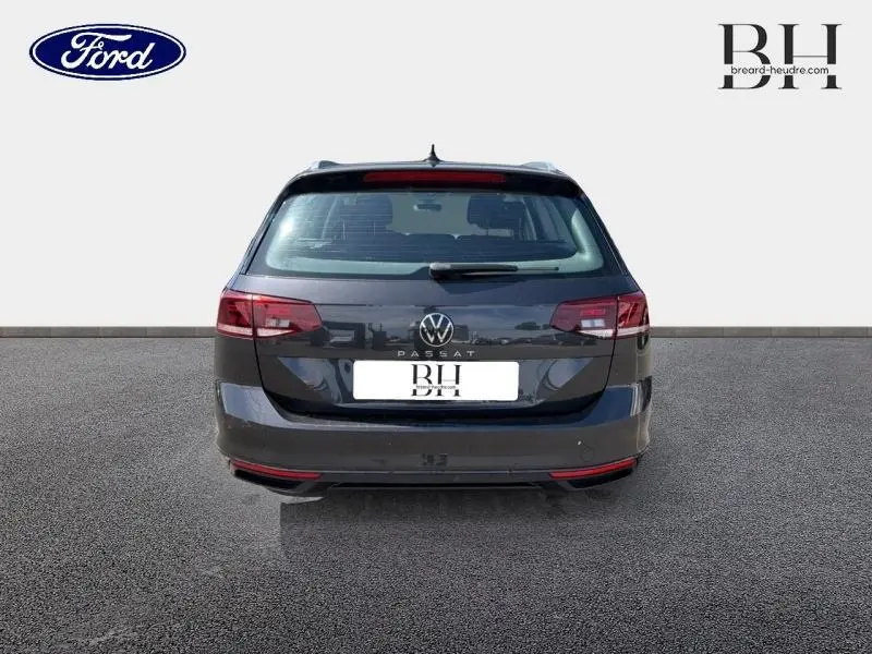 Vue arrière d'une Volkswagen Passat SW gris manganèse métallisé avec feux arrière LED et barres de toit visibles.