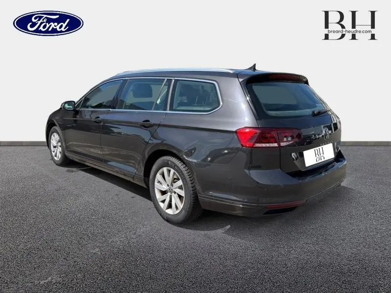 Volkswagen Passat SW gris manganèse métallisé vue 3/4 arrière droit avec barres de toit et jantes alu.