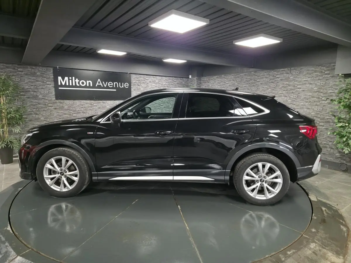 Audi Q3 Sportback noir vue de profil côté gauche, avec jantes 5 branches et vitres arrière surteintées.