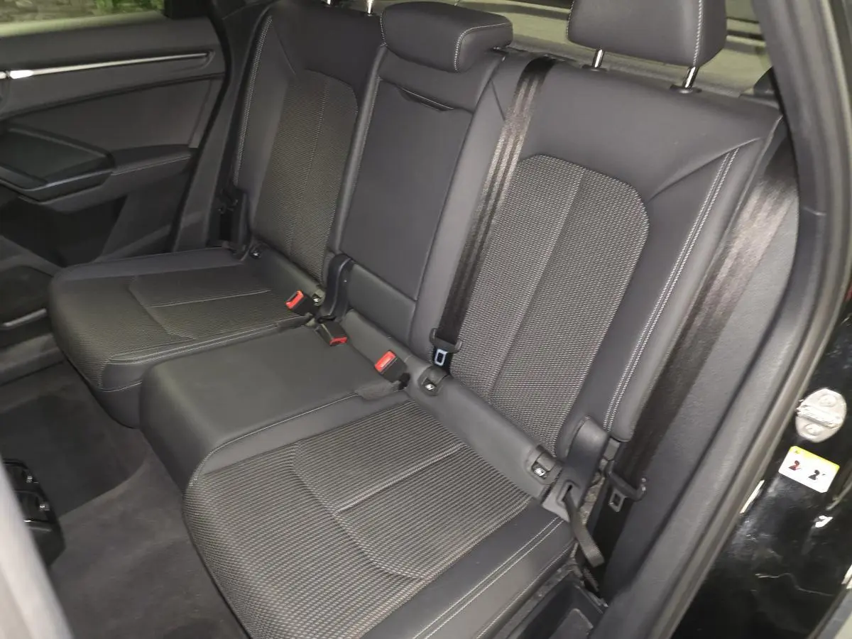 Vue côté droit de la banquette arrière noire de l'Audi Q3 Sportback 2023 avec ceintures et appuie-têtes visibles.