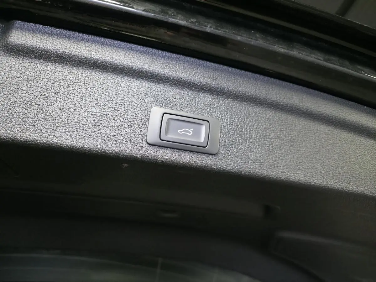 Bouton d'ouverture électrique du hayon sur la partie intérieure noire du coffre d'un Audi Q3 Sportback noir.