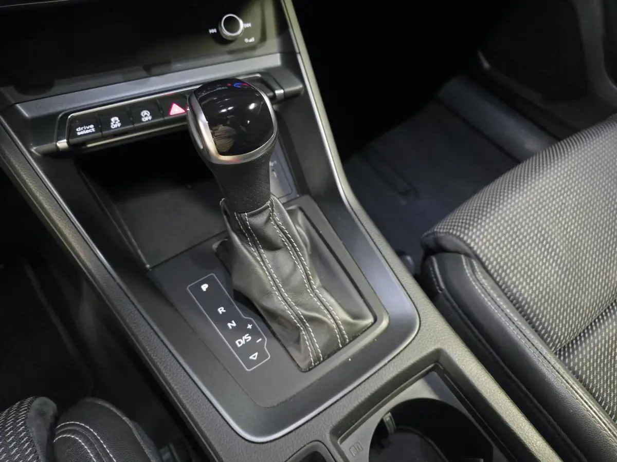 Gros plan sur le levier de vitesse automatique noir et cuir avec surpiqûres blanches dans l’Audi Q3 Sportback 2023.