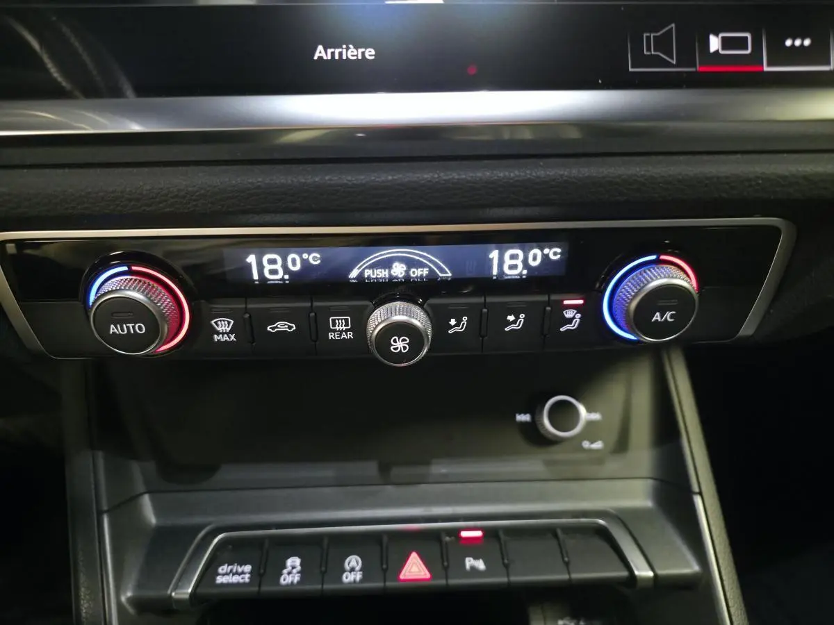 Vue rapprochée de la console centrale de l'Audi Q3 Sportback noire, affichant la climatisation automatique et les commandes.