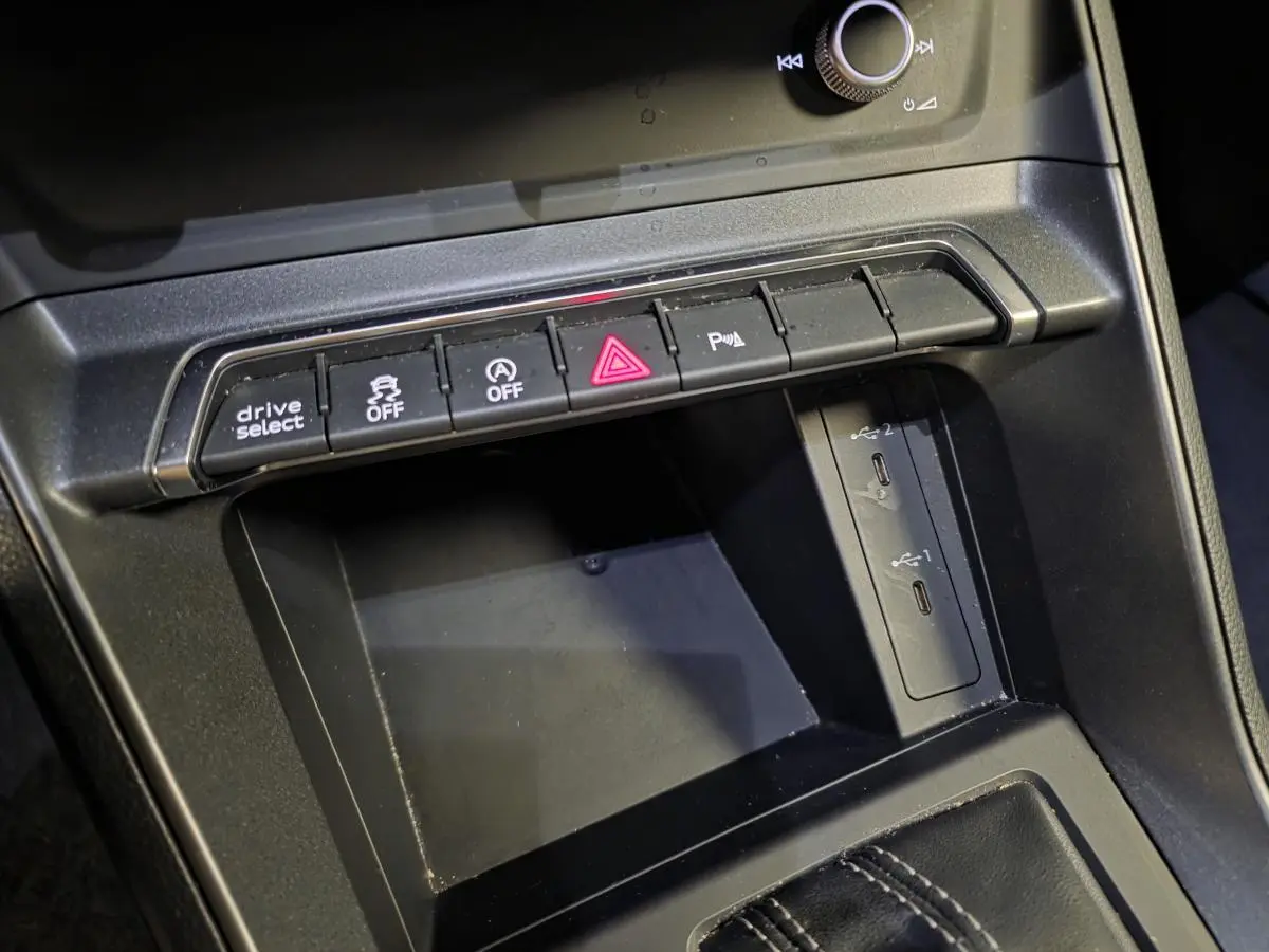 Gros plan sur la console centrale noire de l'Audi Q3 Sportback 2023 avec boutons de contrôle et deux ports USB-C visibles.
