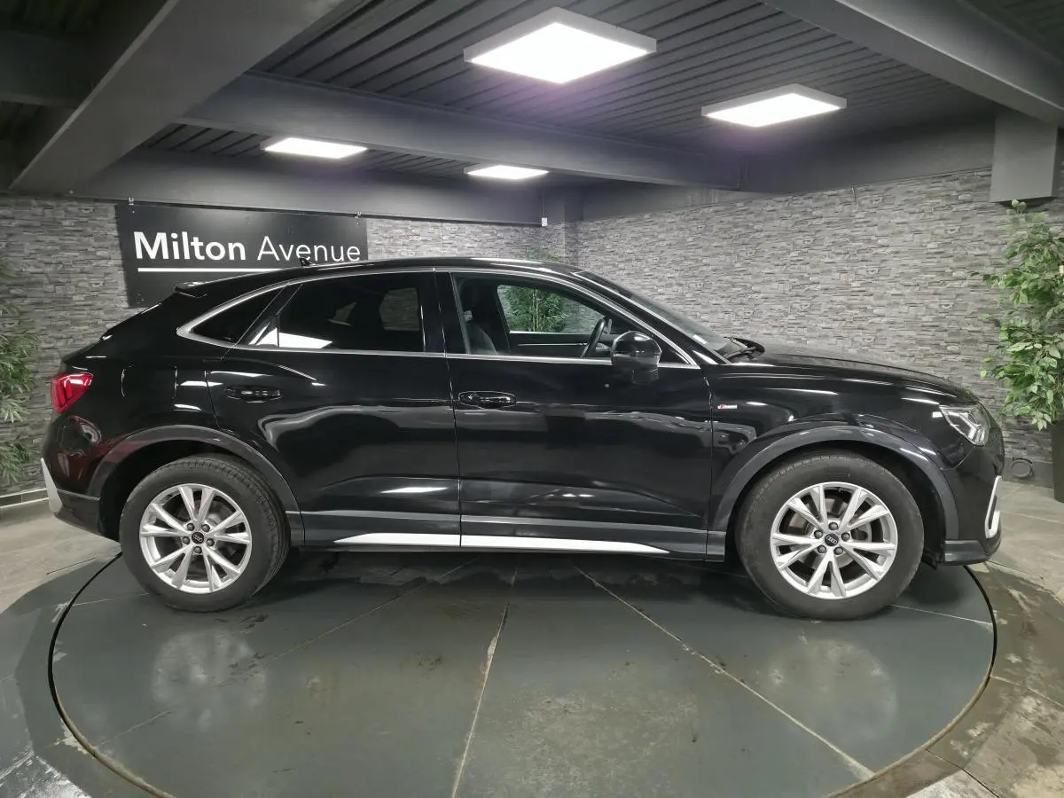 Audi Q3 Sportback noir vue de profil côté gauche, vitres arrière surteintées et jantes 18 pouces en aluminium.