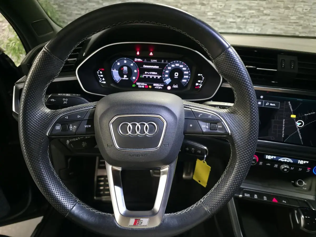 Vue rapprochée du volant cuir perforé noir avec logo S et tableau de bord numérique de l'Audi Q3 Sportback 2023.