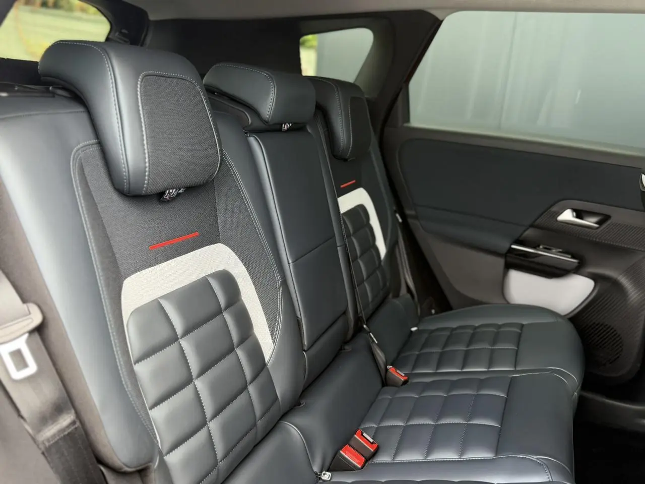 Vue latérale intérieure des sièges arrière en cuir noir et tissu avec surpiqûres et détails rouges du Citroën C5 Aircross.