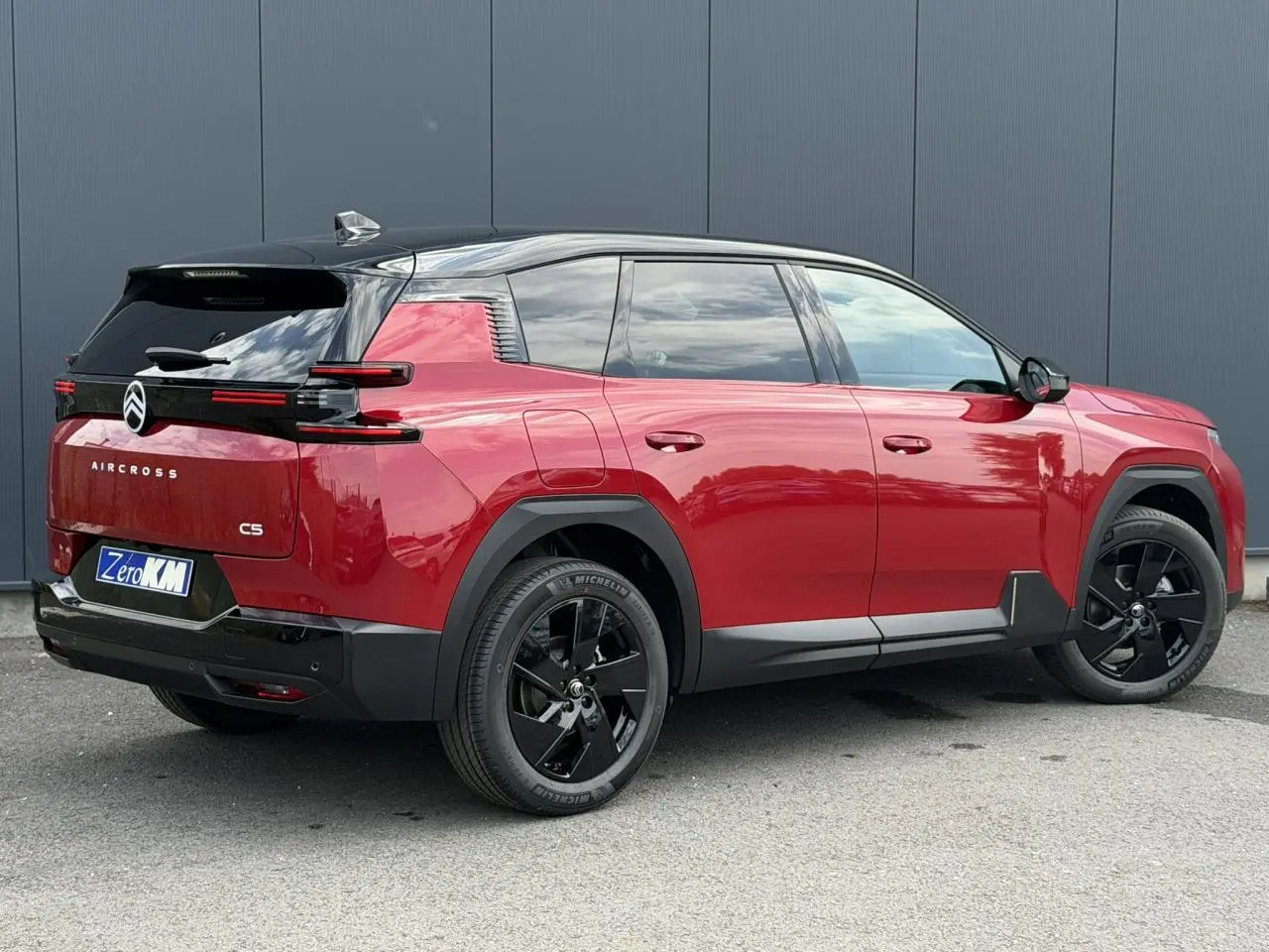 Vue 3/4 arrière droite du Citroën C5 Aircross rouge rubis avec toit noir et jantes alliage noires.