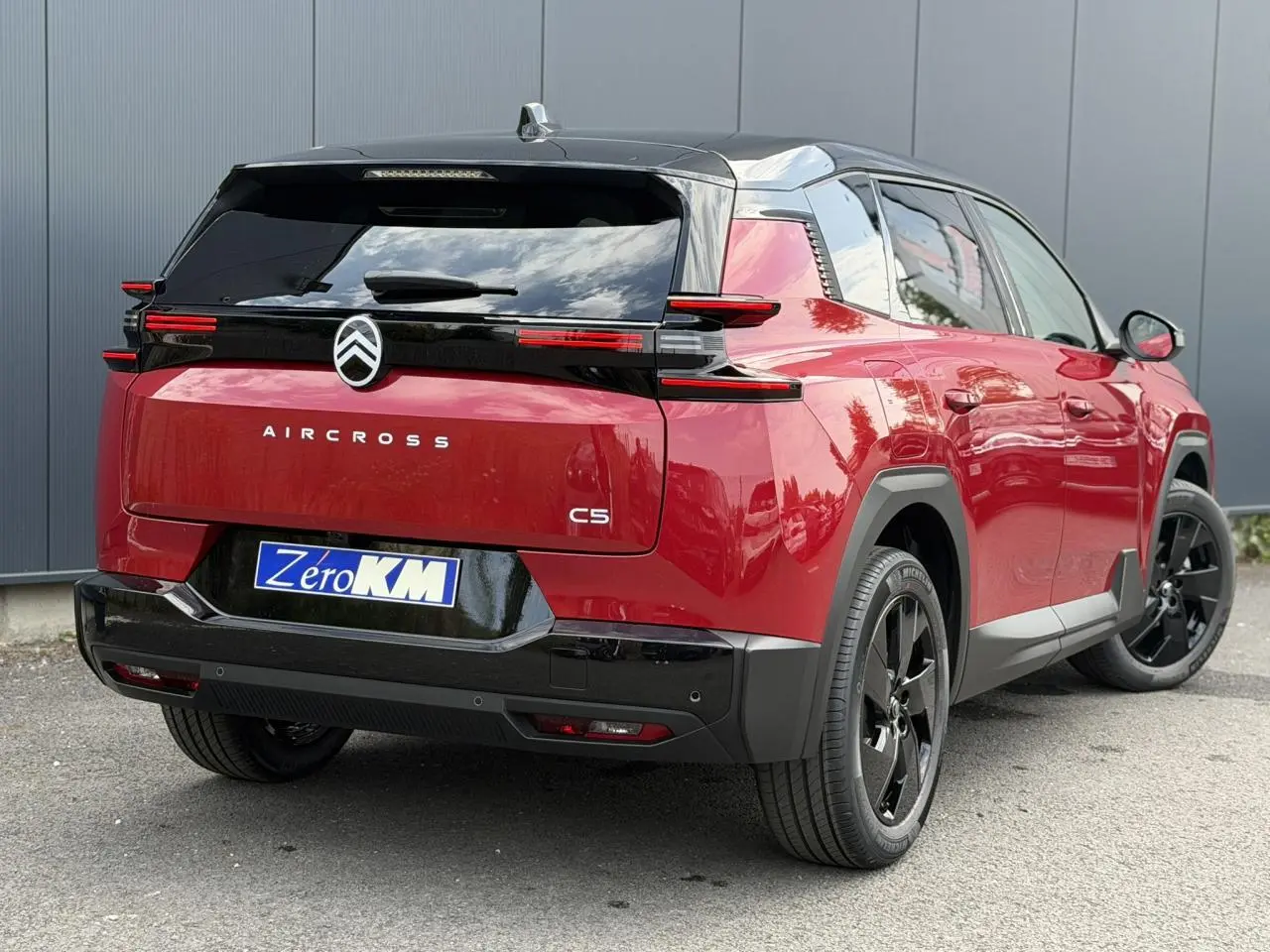 Vue 3/4 arrière droite du Citroën C5 Aircross 2026 rouge rubis avec toit noir et jantes alliage noires.