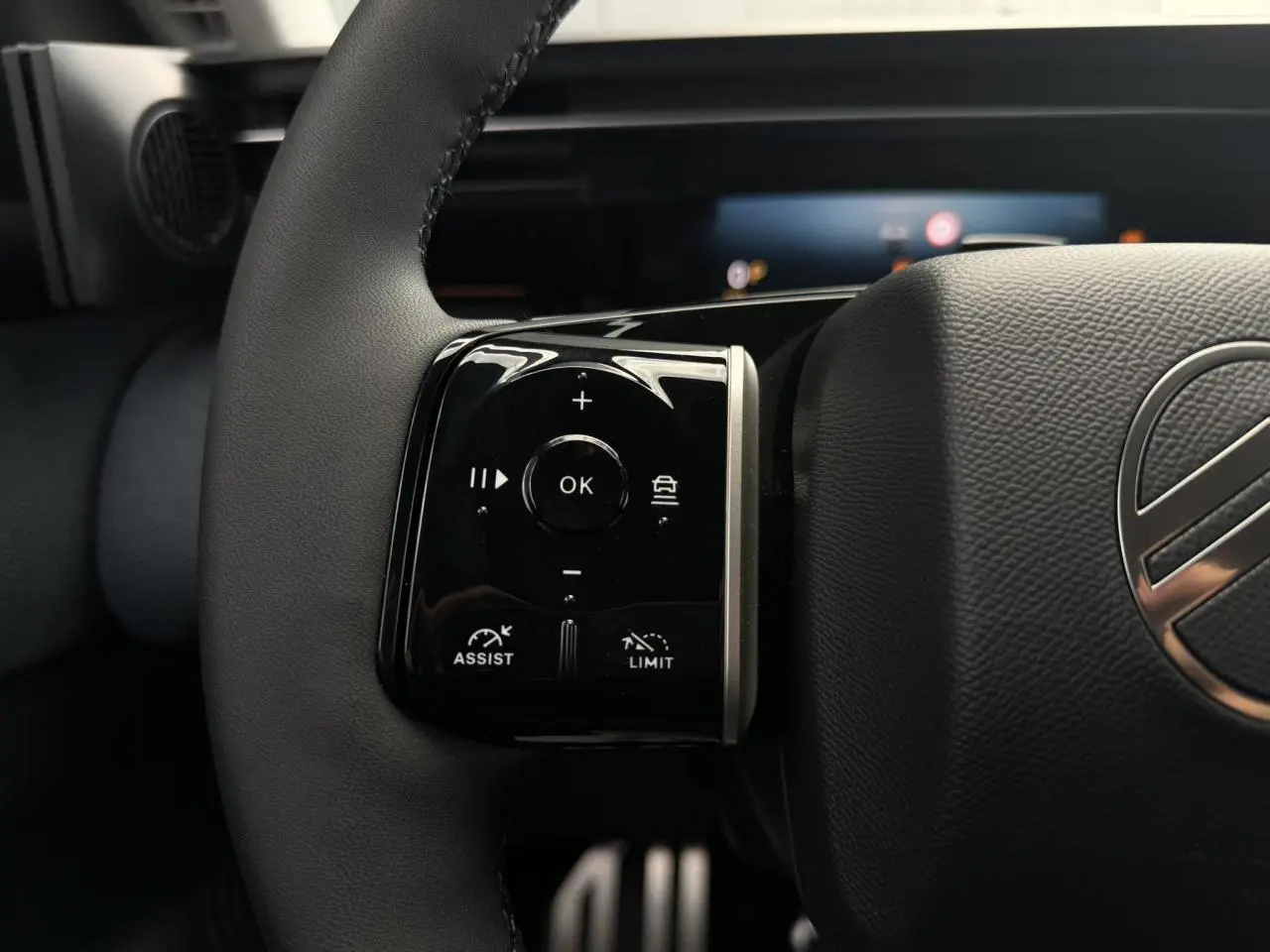 Gros plan sur les commandes noires au volant cuir noir du Citroën C5 Aircross hybride, avec logo argenté visible.