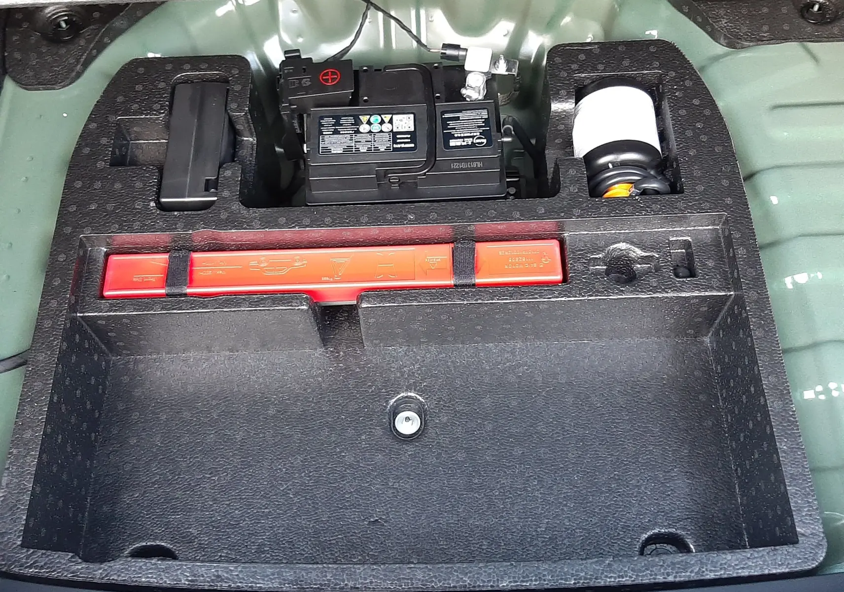 Vue rapprochée du compartiment de rangement arrière du MG Motor ZS Emerald Green 2026, montrant la batterie et les outils.