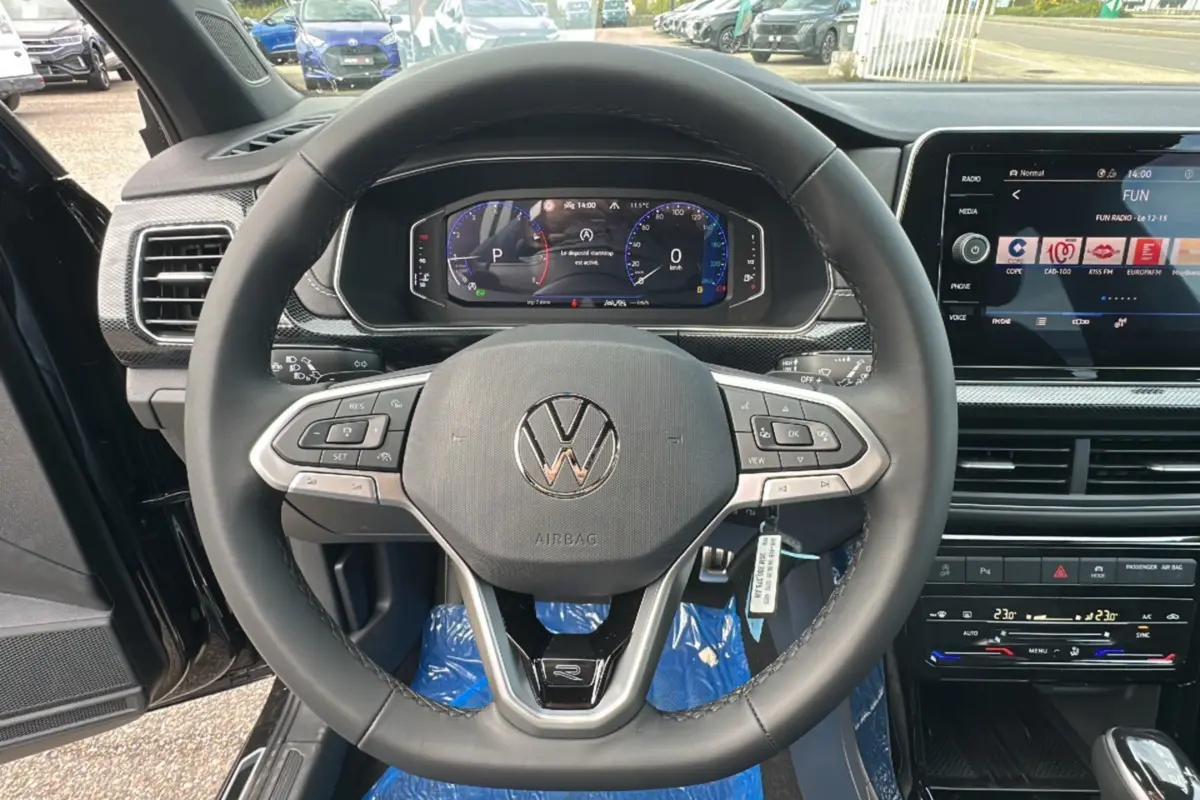 Vue intérieure centrée sur le volant cuir multifonctions et tableau de bord digital du Volkswagen T-Cross noir intense 2025.