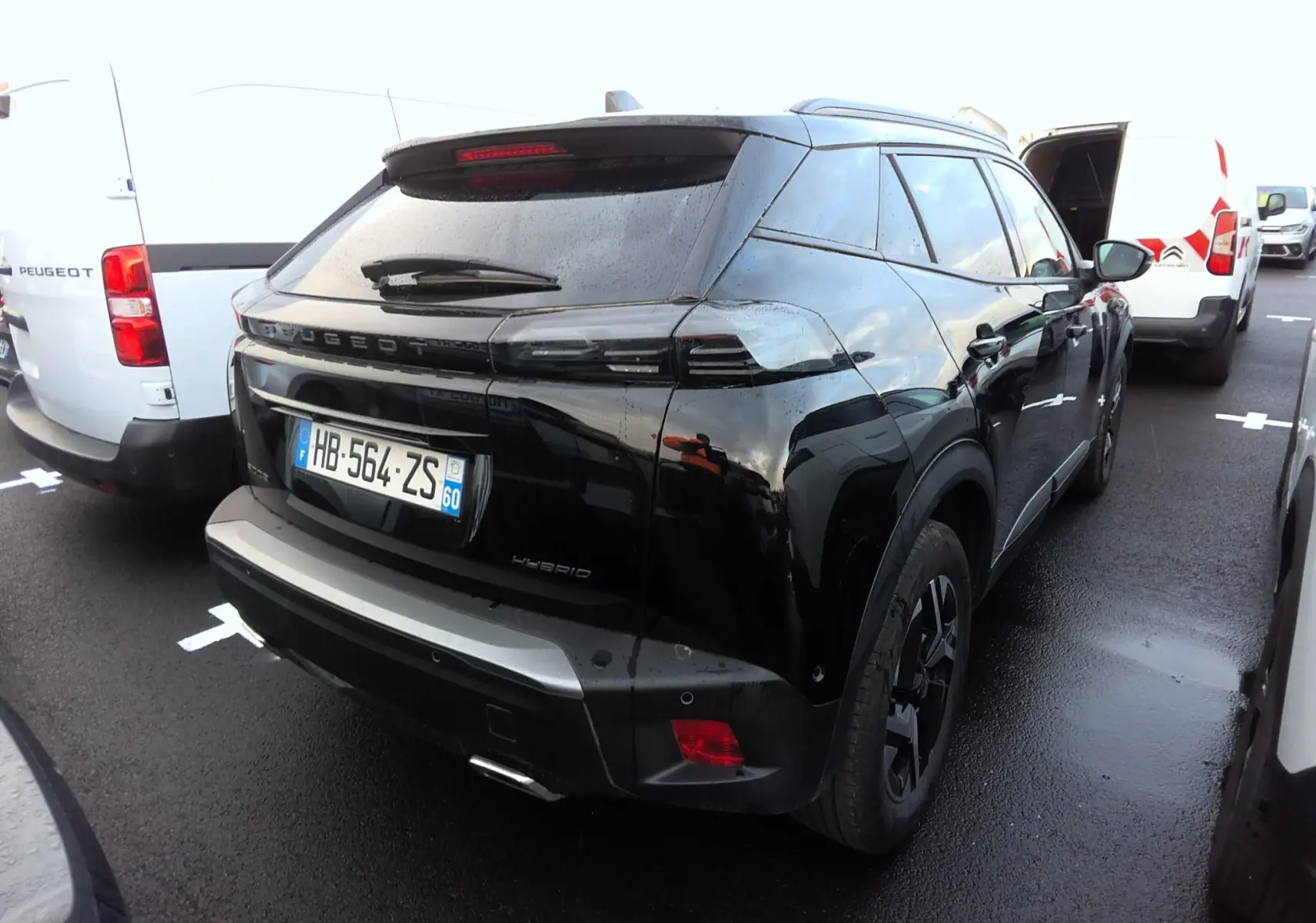 Vue 3/4 arrière droite d'un Peugeot 2008 noir hybride avec becquet et sorties d'échappement chromées.