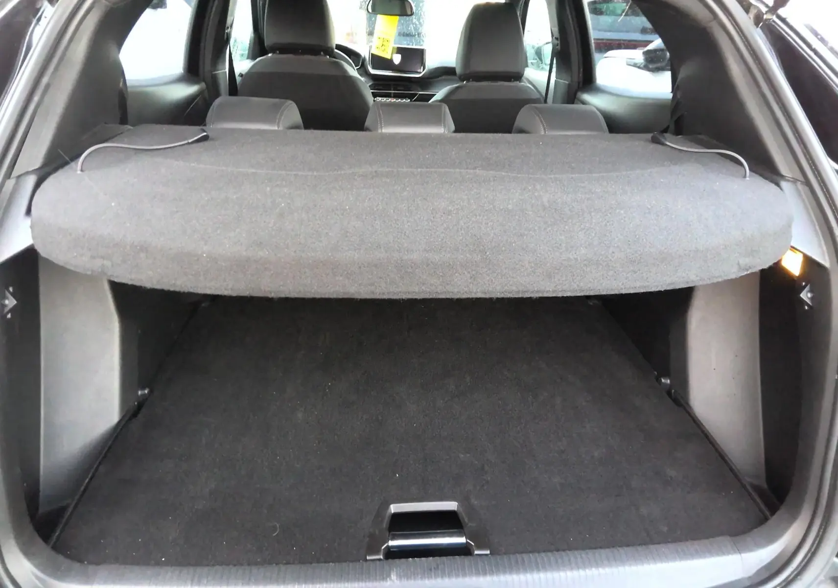 Vue arrière du coffre noir du Peugeot 2008 1.2 HYBRID 145 e-DCS6 Allure avec cache-bagages déployé.