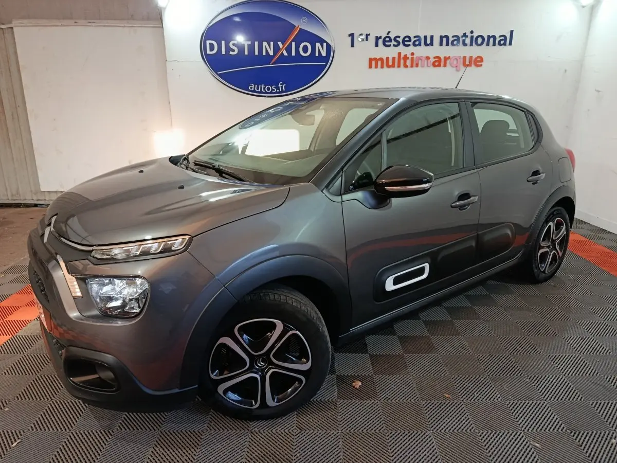 Citroën C3 gris foncé vue 3/4 avant droit, avec protections latérales noires et jantes distinctives.