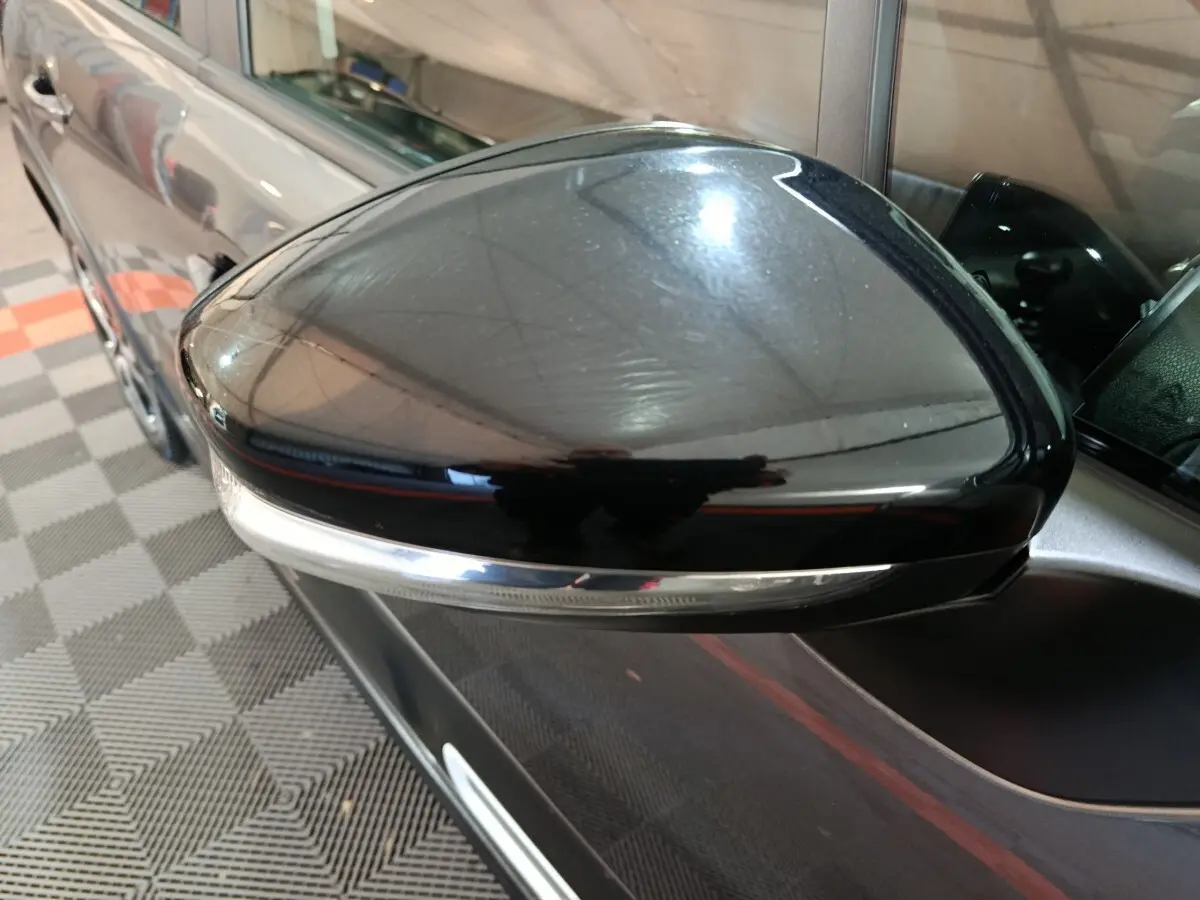 Gros plan sur le rétroviseur droit noir brillant d'une Citroën C3 gris foncé, avec clignotant intégré.