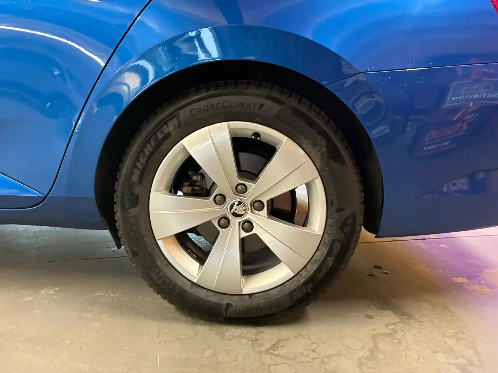 Gros plan sur la roue arrière droite d’une Skoda Superb Combi bleu, avec jante alliage argentée et pneu Michelin.